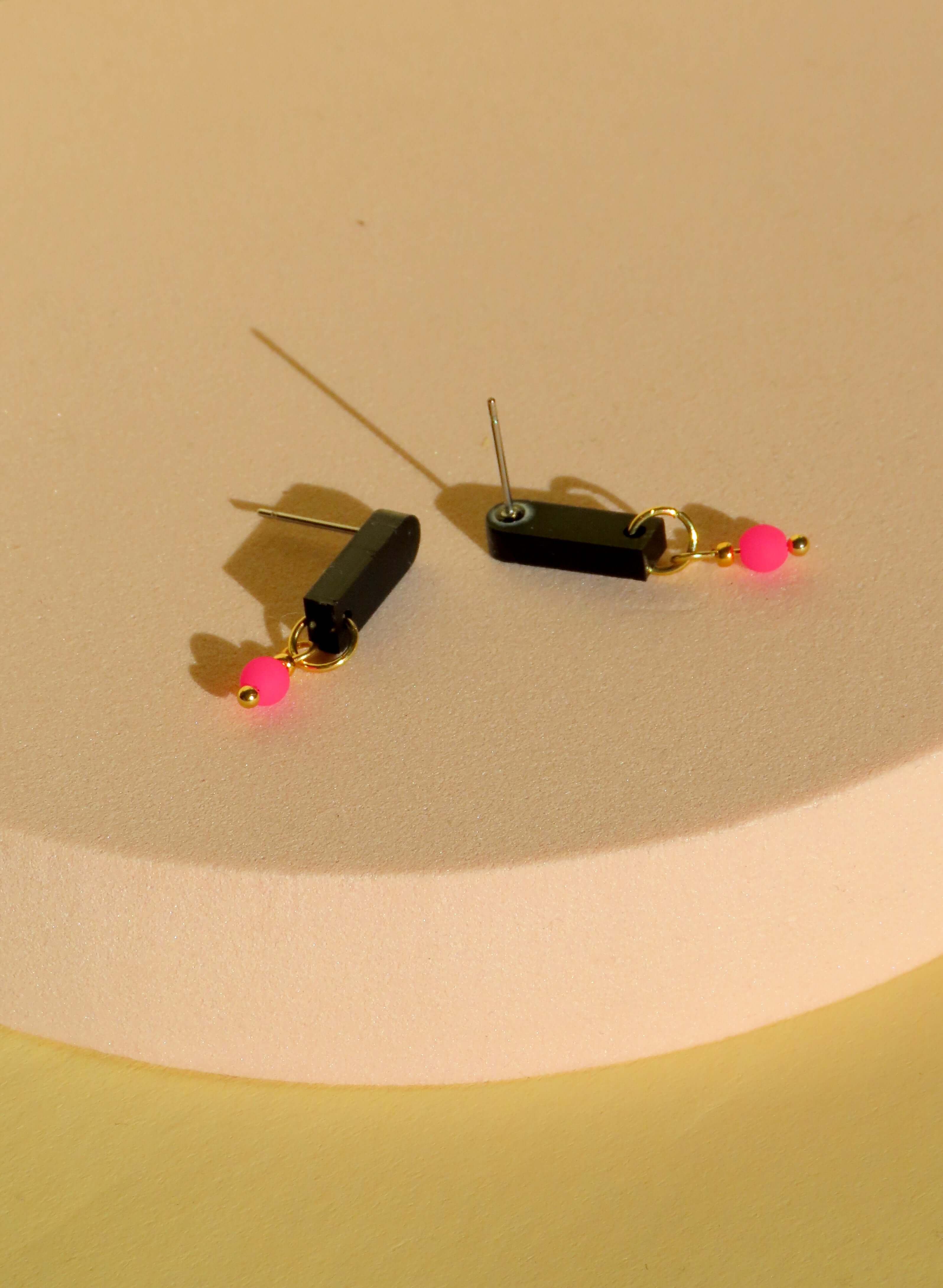 Handgefertigte Acrylohrringe in Schwarz und Neonpink mit Edelstahl-Elementen und filigraner Form