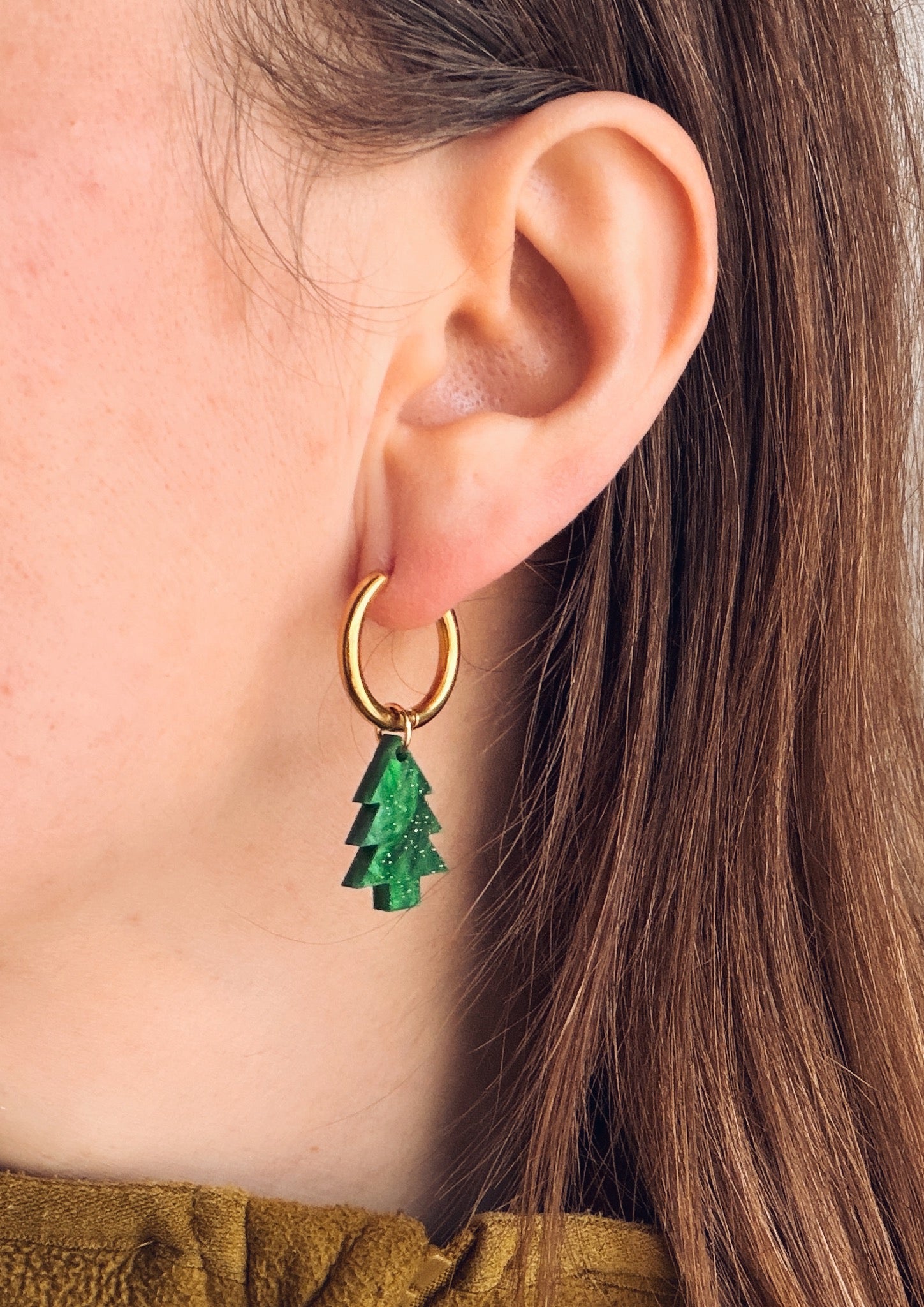 Leichte Edelstahlcreolen in Goldoptik mit kleinen tannengrünen Acryl-Tannenbäumen und dezentem Glitzereffekt