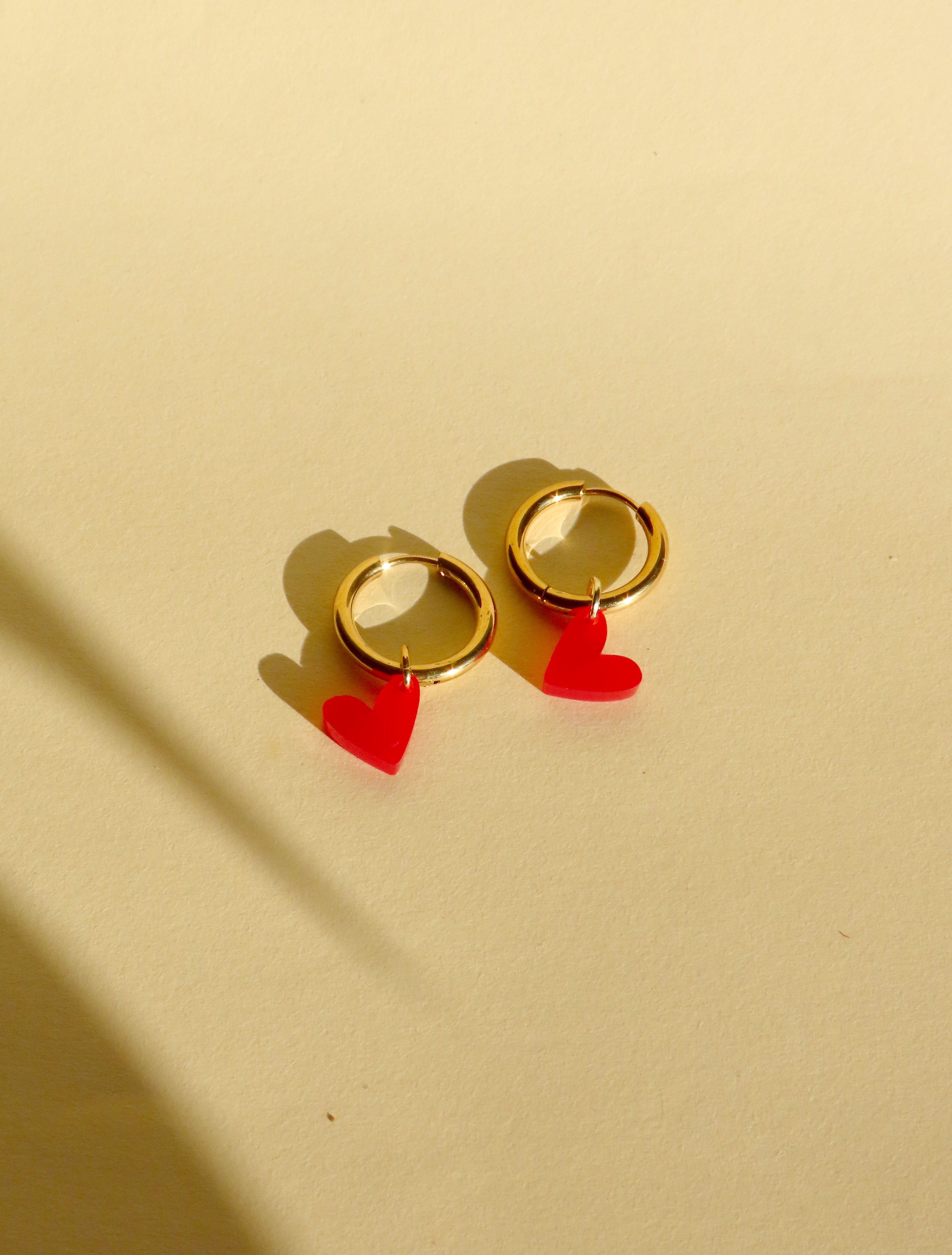 Vergoldete Edelstahlcreolen mit feuerrotem Acrylherz als kleiner Anhänger