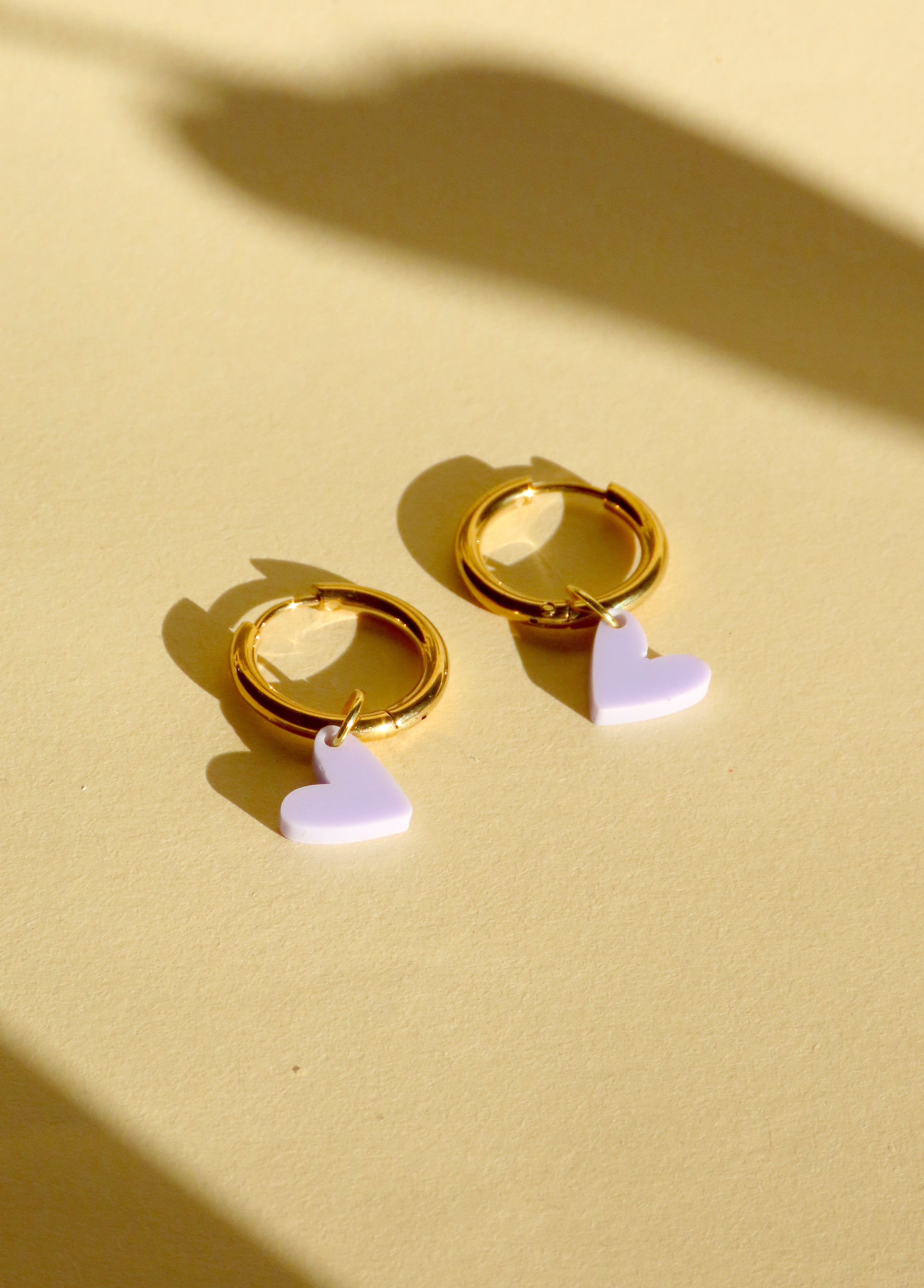 Vergoldete Edelstahlcreolen mit kleinem fliederfarbenem Acrylherz als Anhänger