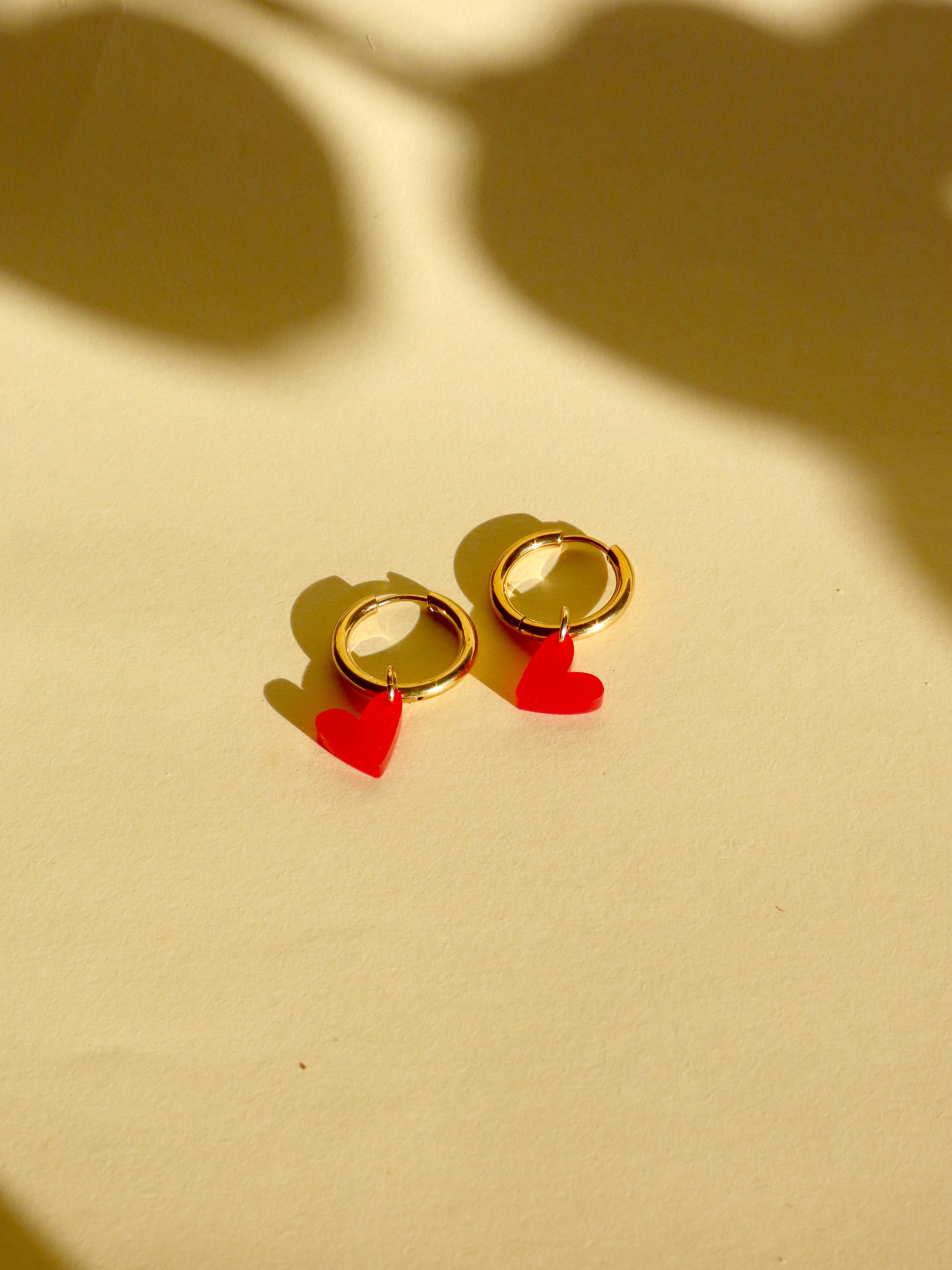 Runde Edelstahlcreolen in Goldoptik mit feuerrotem Herzanhaenger aus Acryl