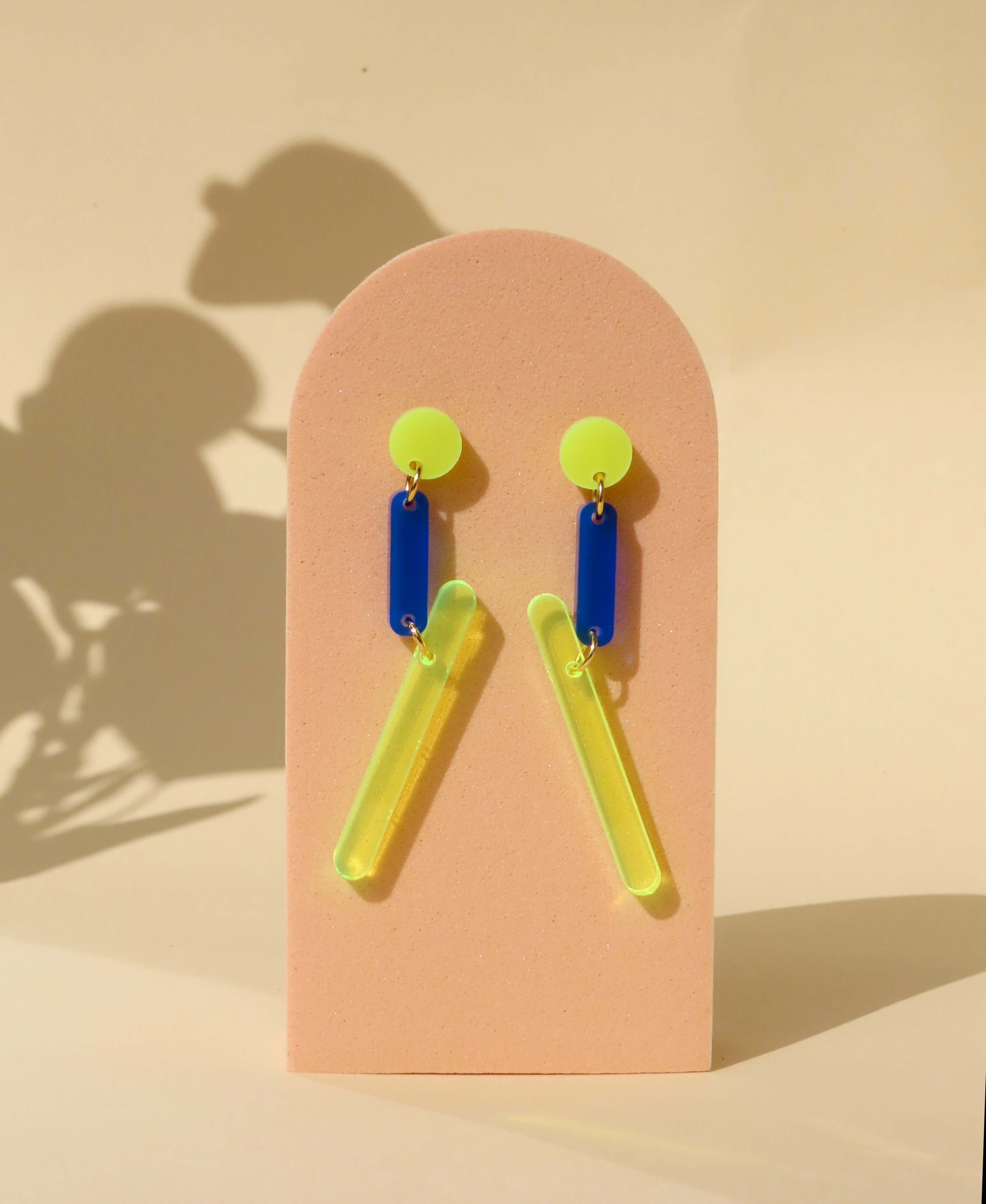 Kunstedition Ohrring in leuchtendem Neongelb und tiefem Blau, mit Edelstahl-Stecker und transparentem Anhänger