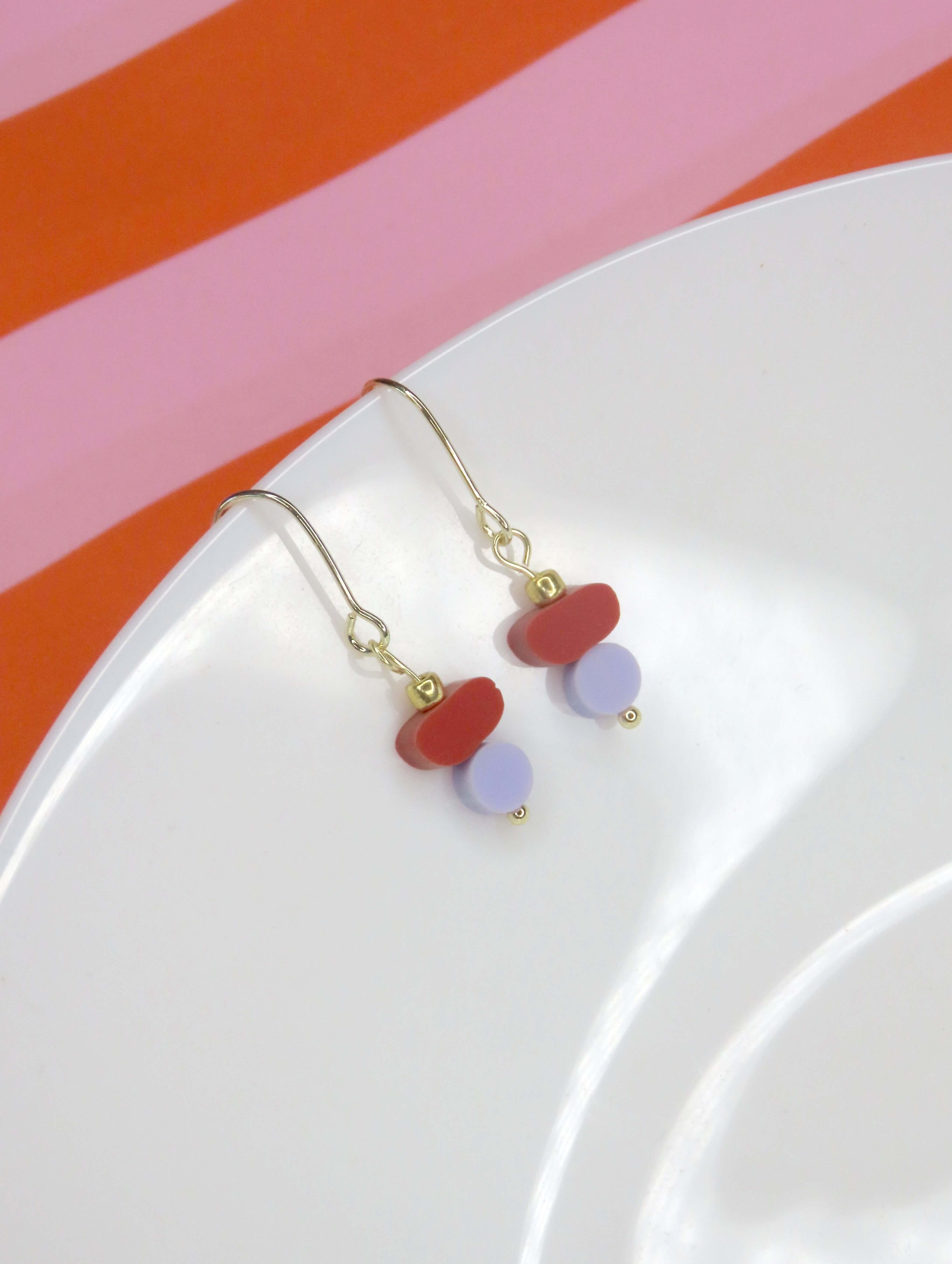 Ohrhänger aus rotem und lila Acryl mit goldfarbenem Haken in minimalistischem Design