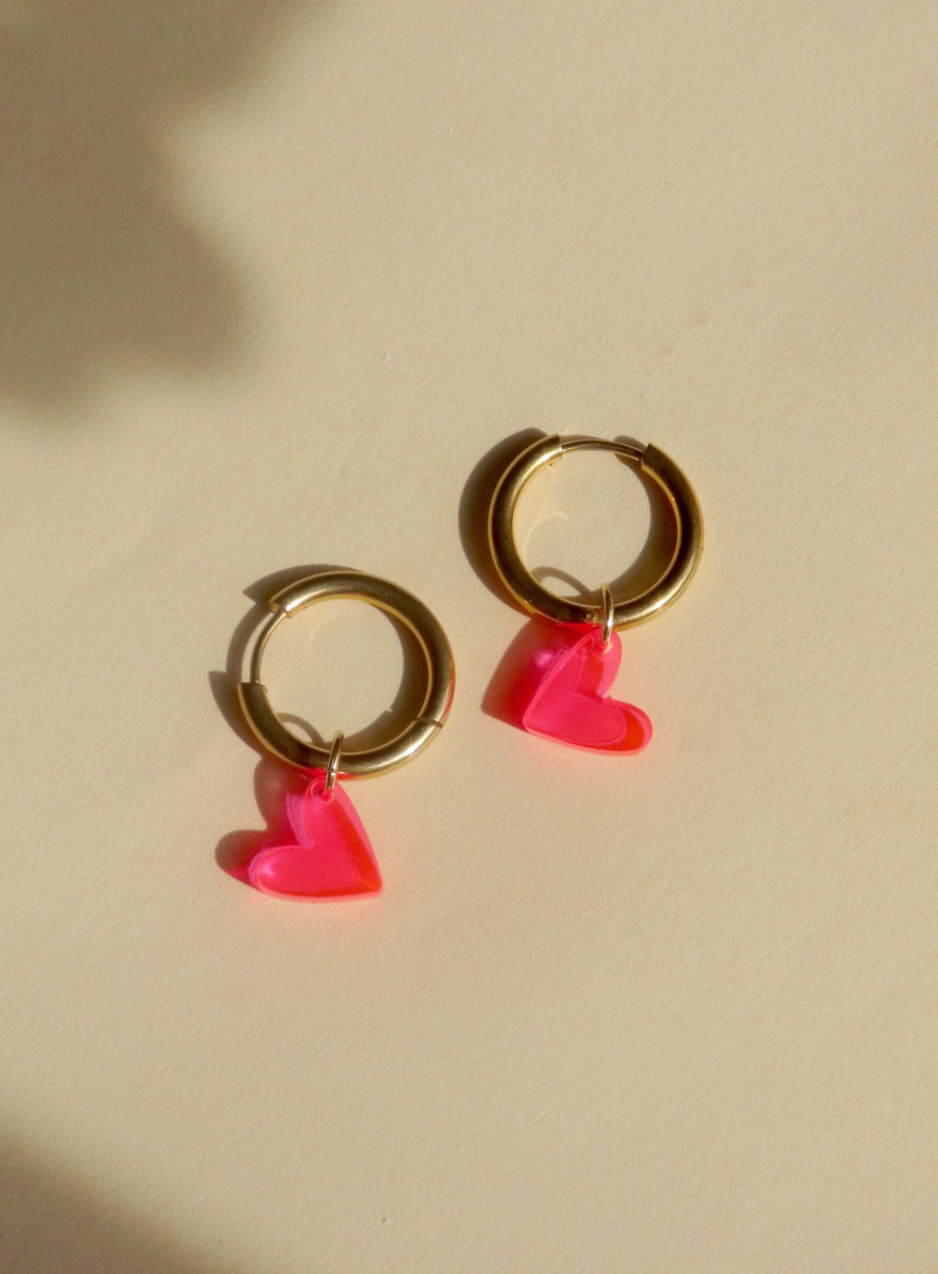 Verspielte Creolen mit transparenten Herzanhängern in Neon Pink und goldglänzendem Edelstahl