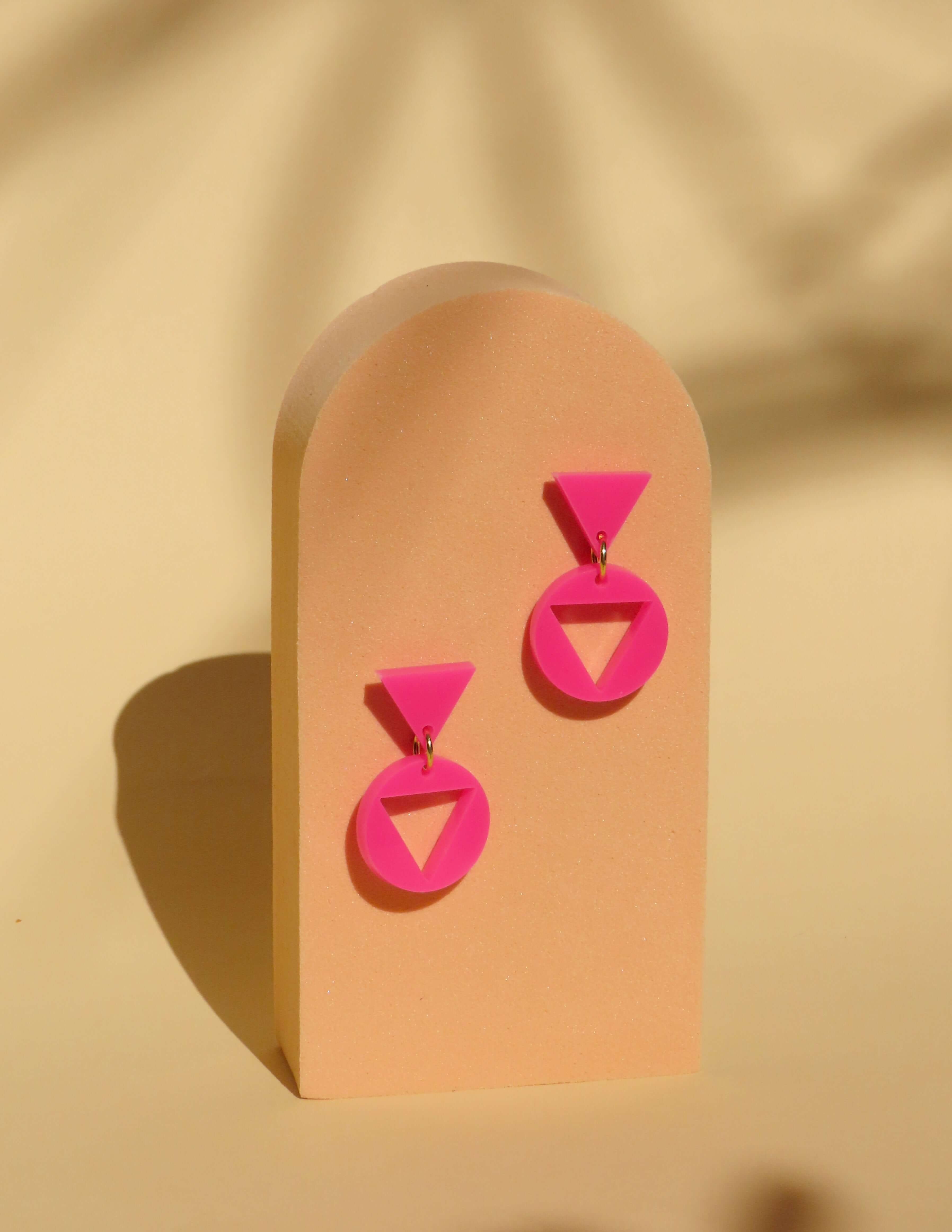 Pinkfarbene Acryl Ohrhänger im grafischen Design mit Dreieck oben und Kreis unten, klarer Kontrast und präzise Kanten