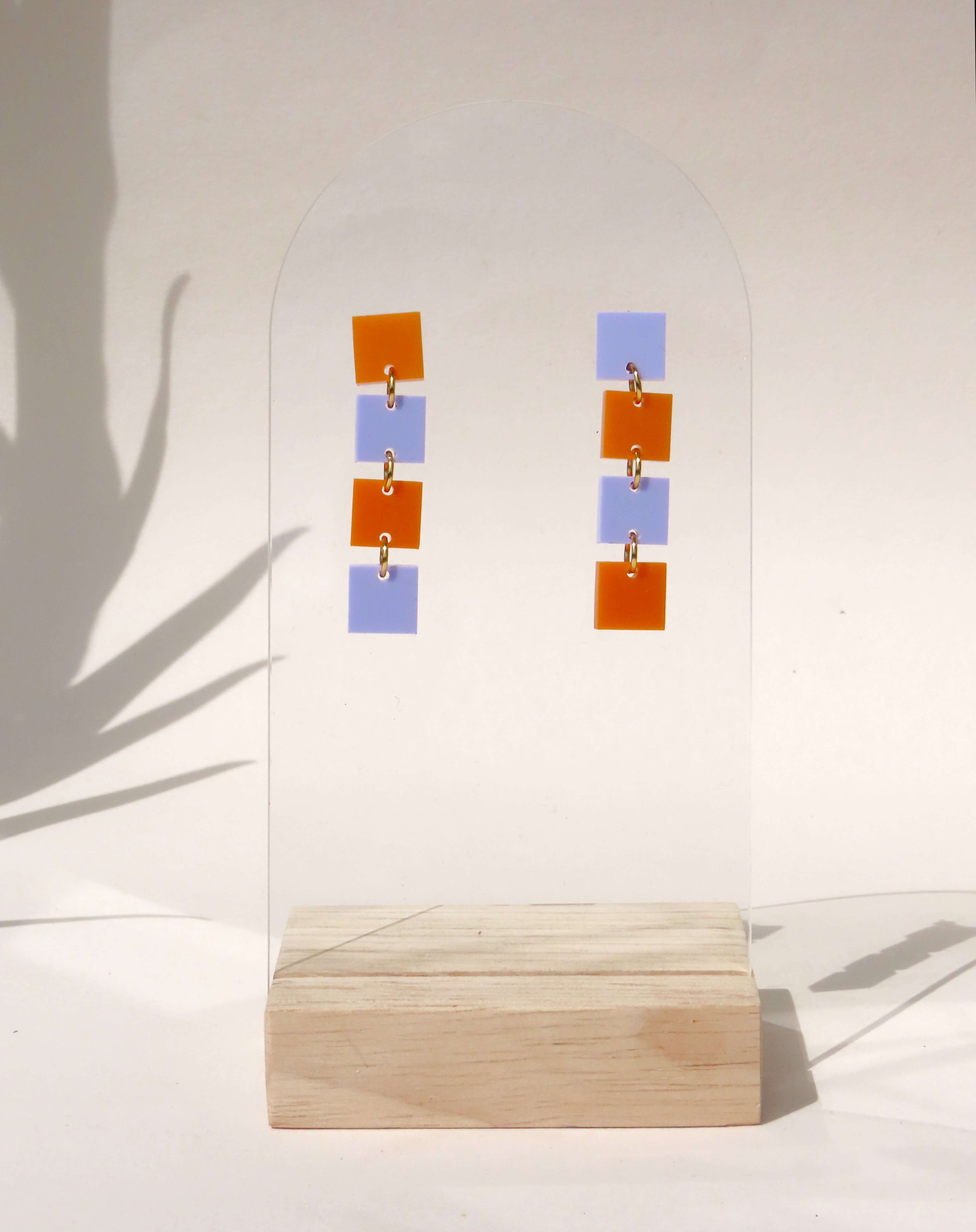 Leichte Edelstahl-Ohrringe aus Acryl in kräftigem Orange und sanftem Flieder mit klarer, vertikaler Linienführung