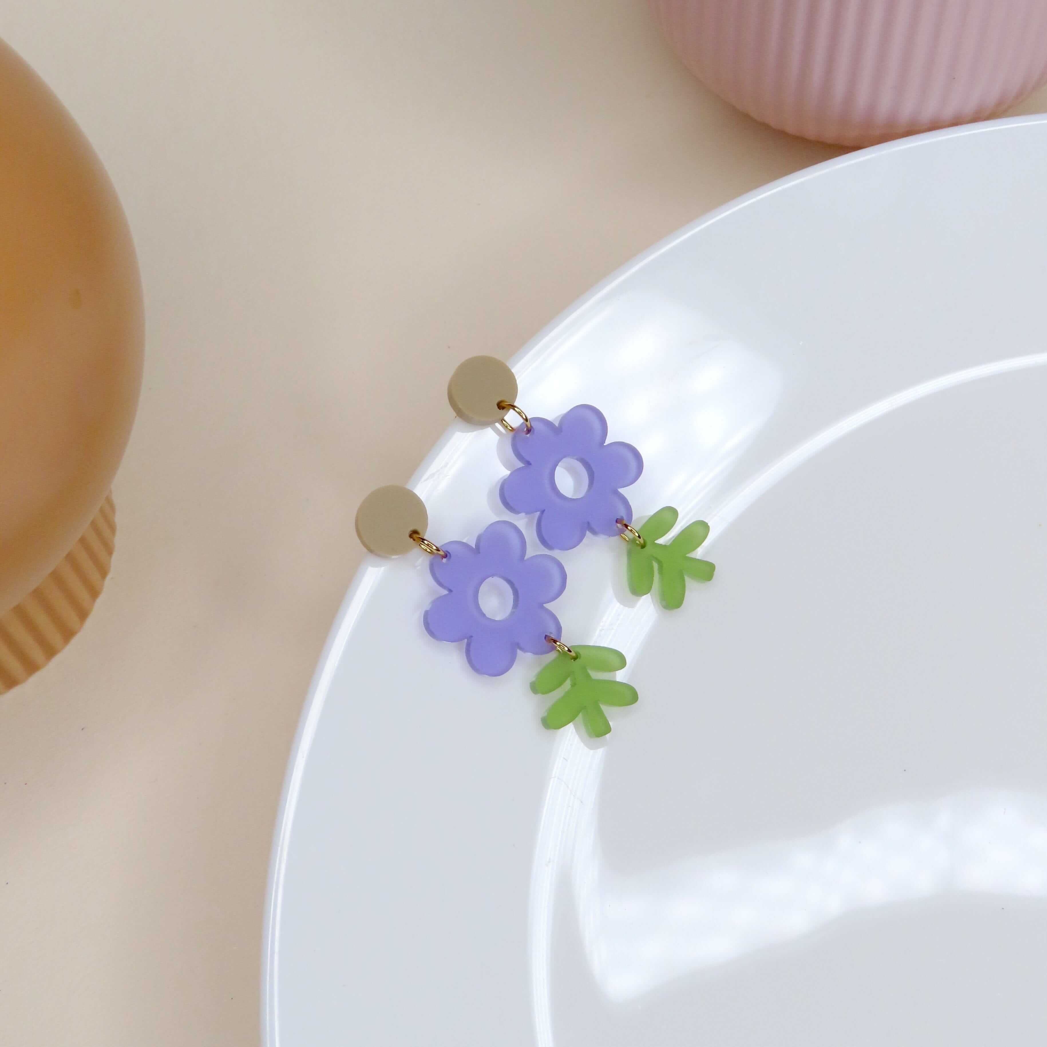 Handgemachte Statement Ohrringe in Blütenform, violett mit grünem Blätteranhänger
