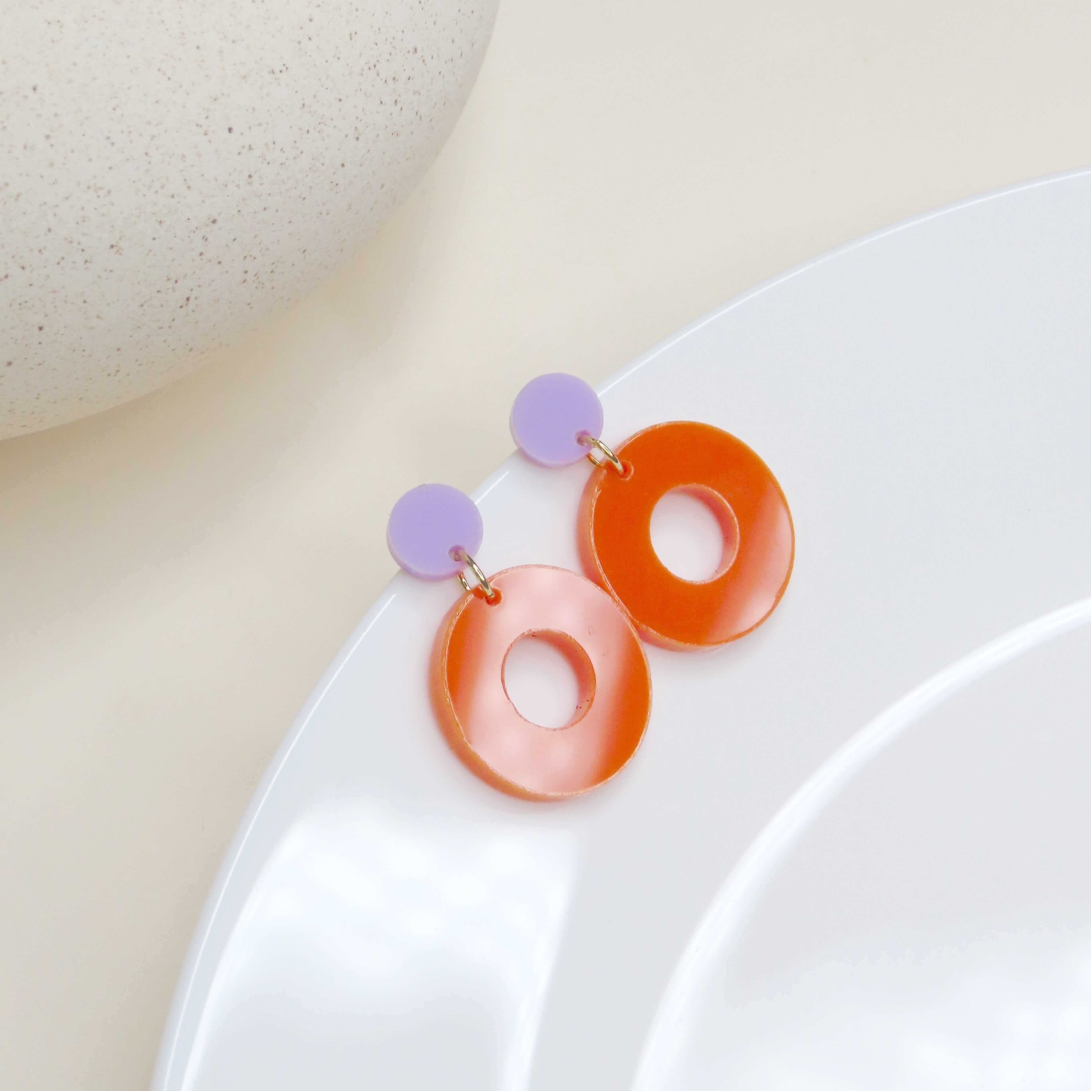 Leichte Ohrringe in Kreis-in-Kreis-Optik mit fliederfarbenem Stecker und großem orangem Acrylring