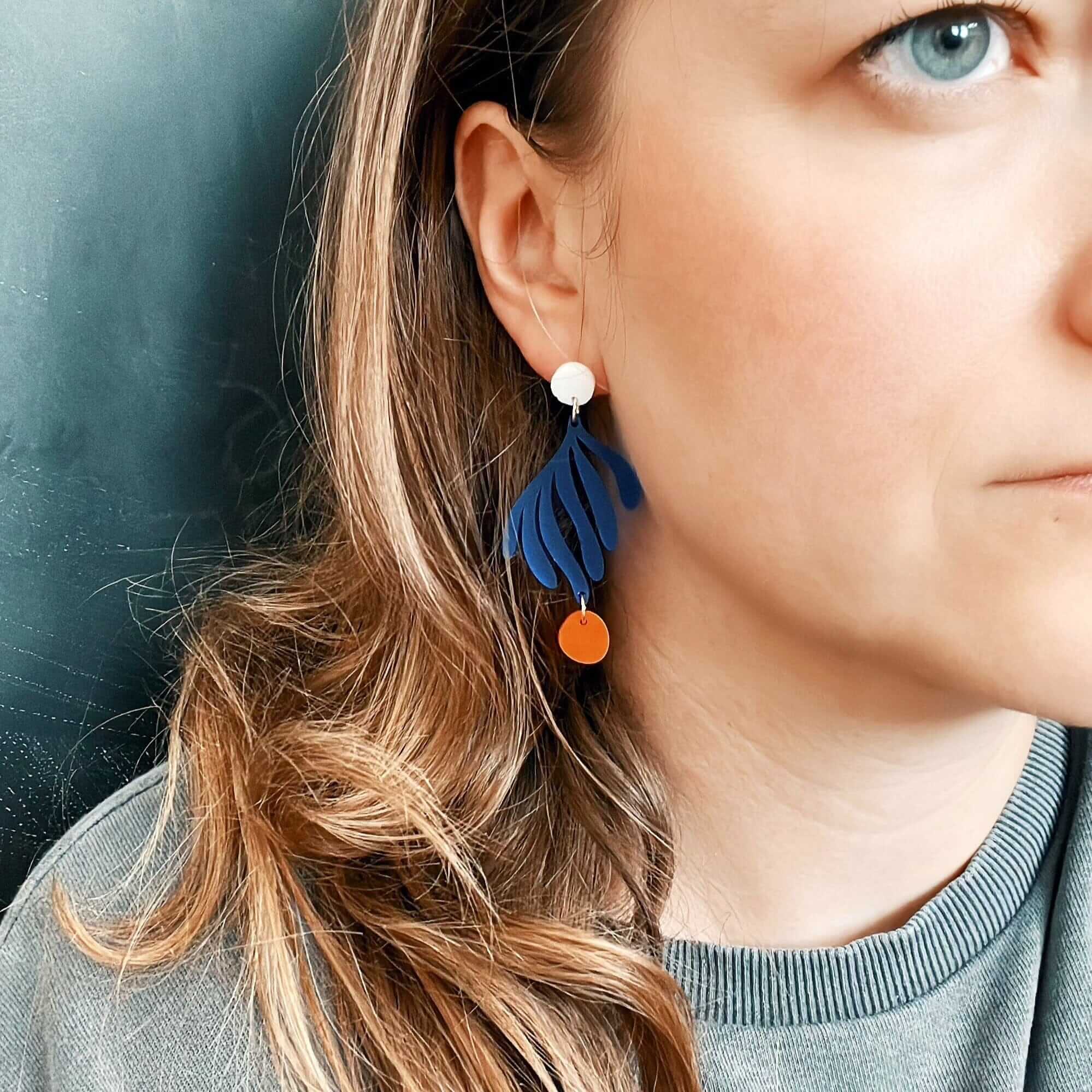 Moderne Acryl-Ohrringe in Matisse-Optik mit filigranen blauen Formen und orangefarbenem Element