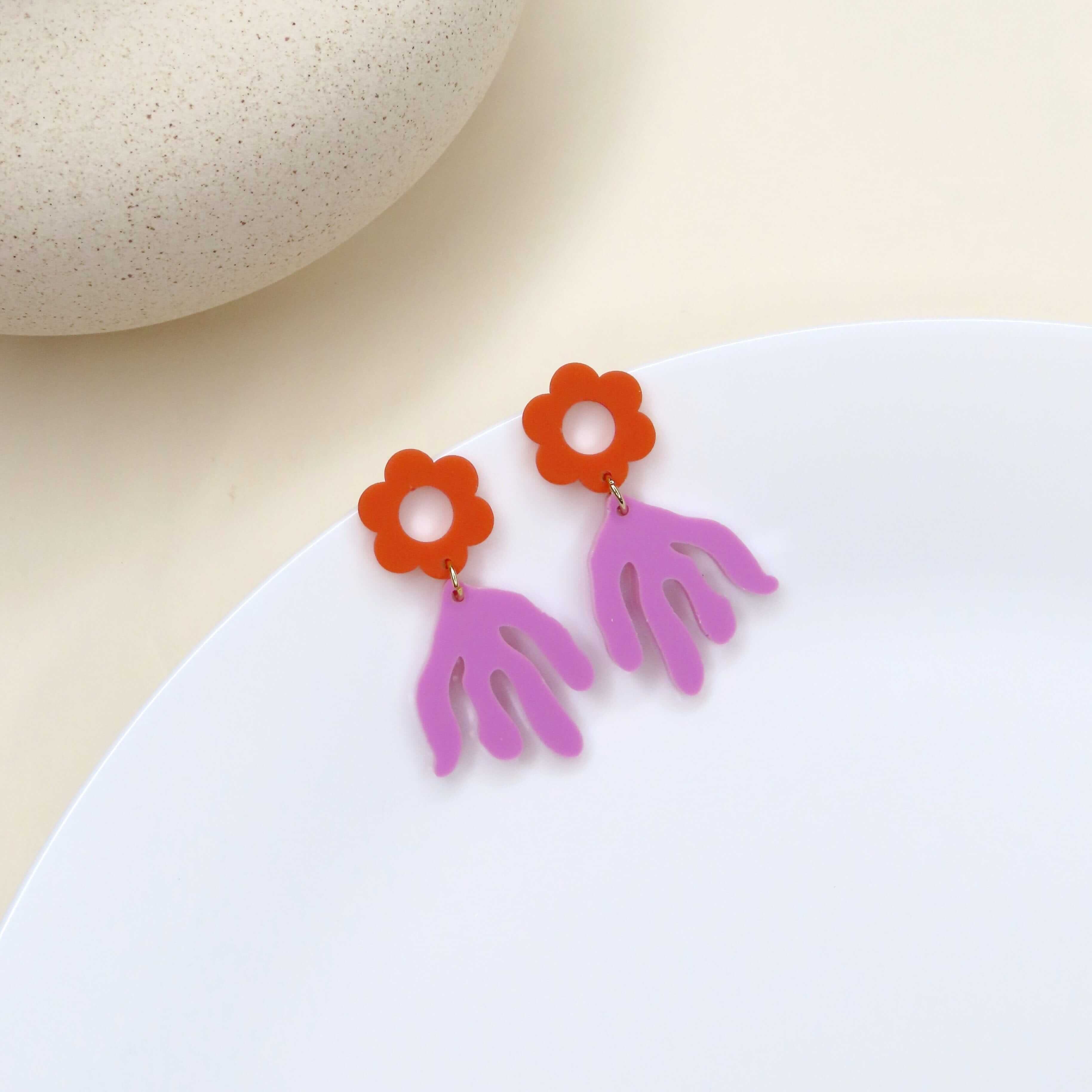 Künstlerische Ohrringe mit violetter Handform und orangeroter Blume aus Acryl