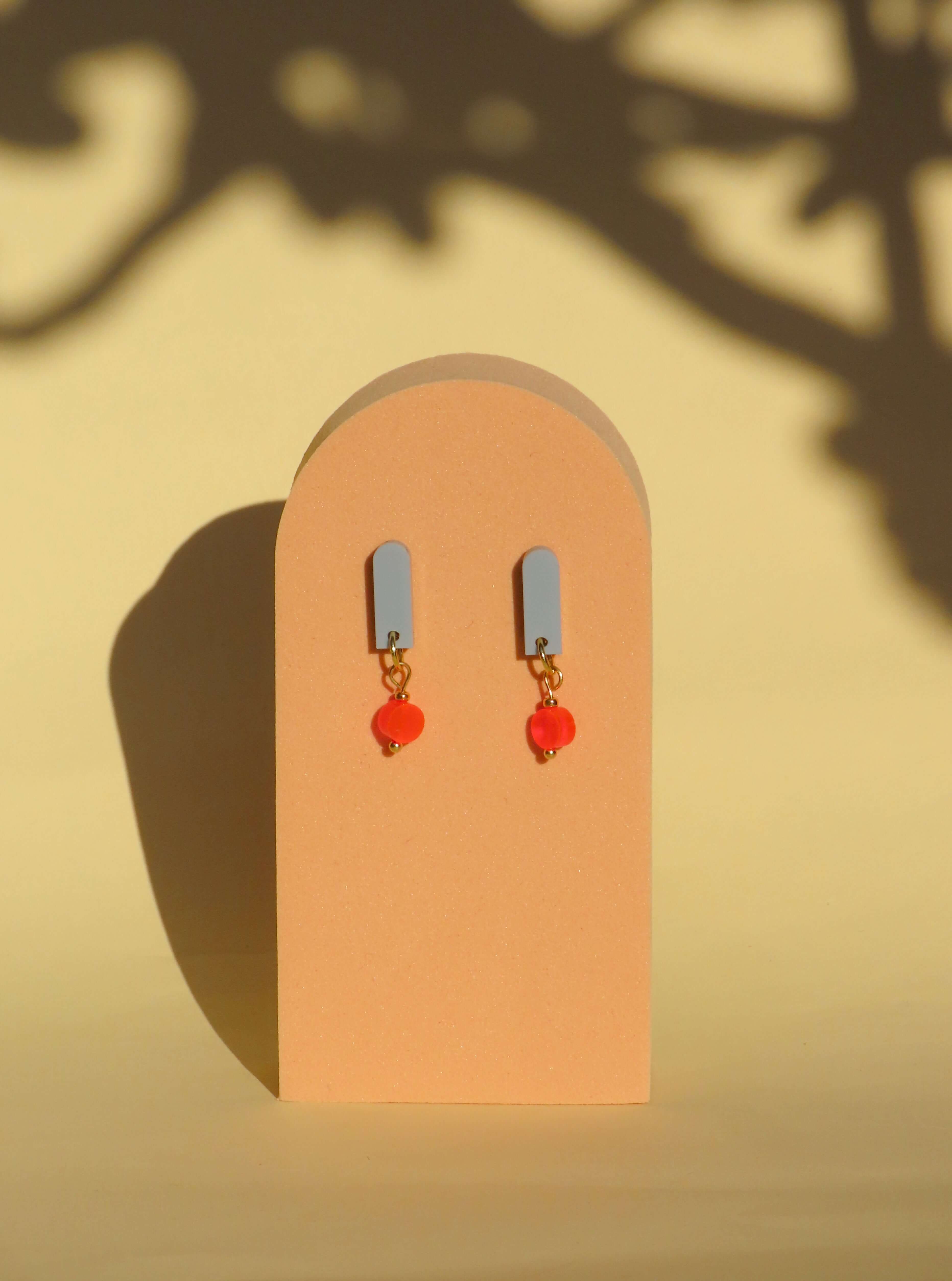 Handgemachte Salbei Neon Orange Paula Ohrringe aus Acryl und Edelstahl, elegantes Design mit rotem Glasherz.