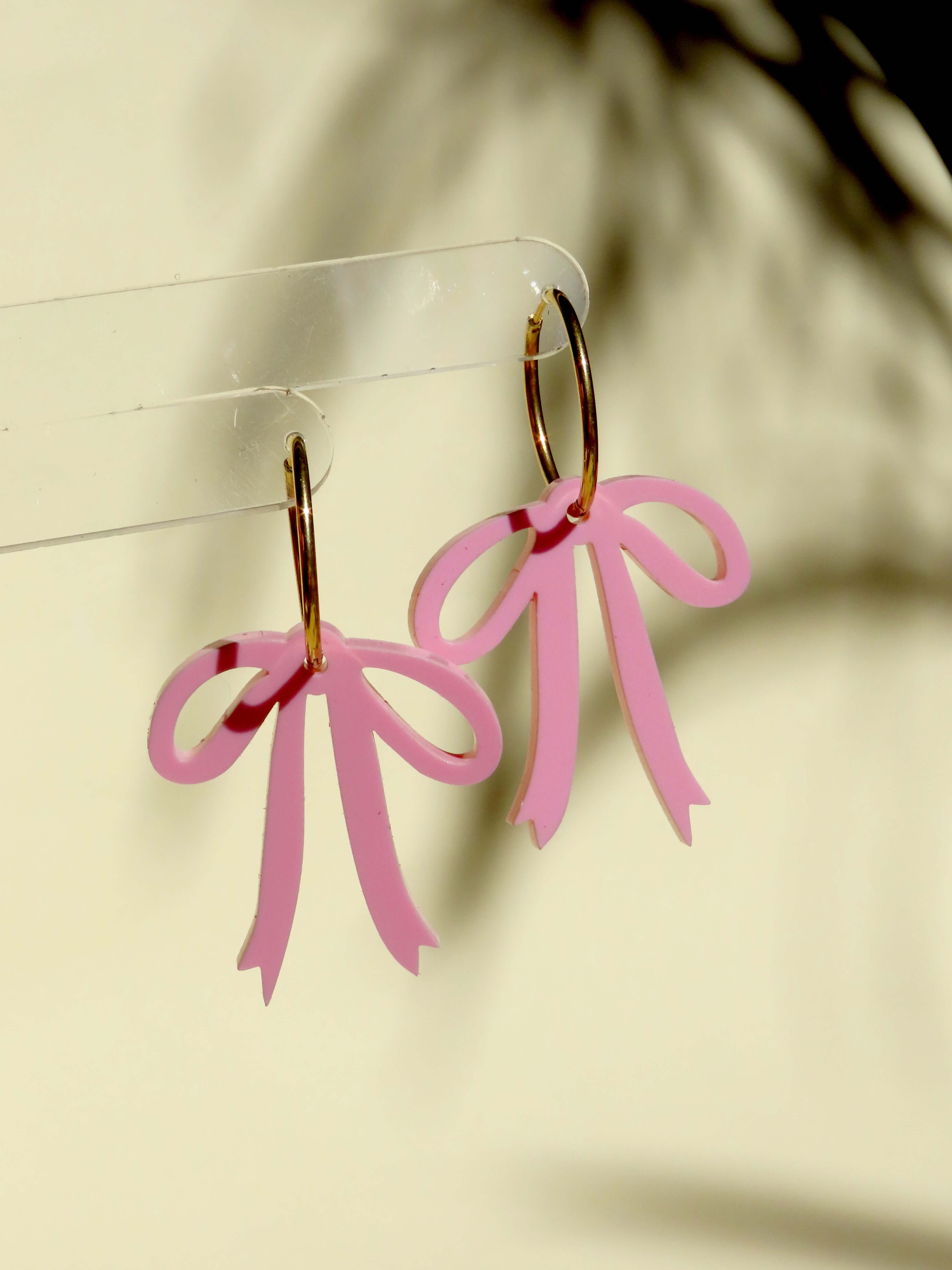 Verspielte Creolen mit rosa Schleifen, handgefertigt aus vergoldetem Edelstahl und Acryl, ideal für stilvolle Akzente.