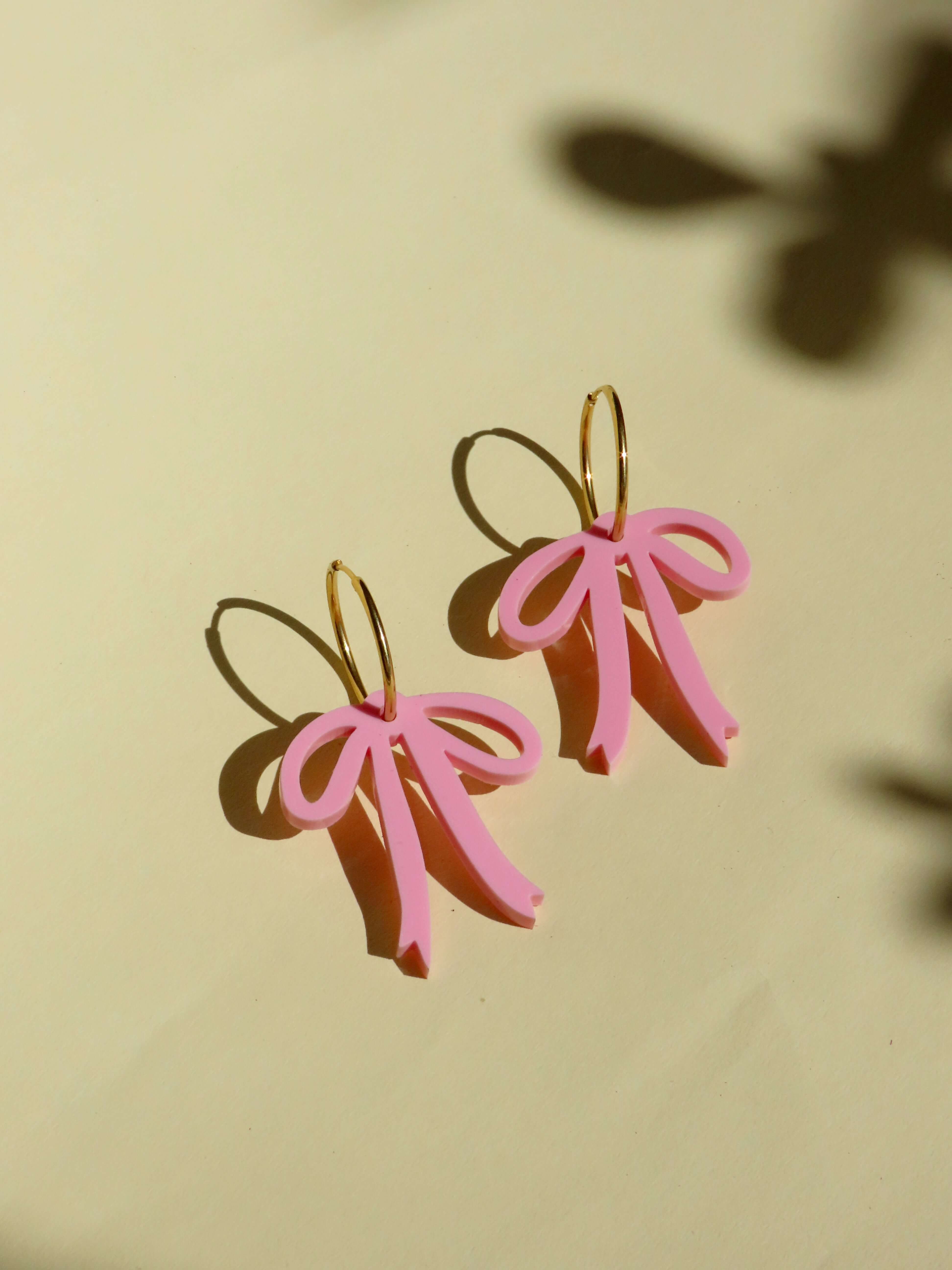 Verspielte rosa Schleifen-Creolen in Gold, handgefertigte Statement-Ohrringe aus Acryl und Edelstahl.