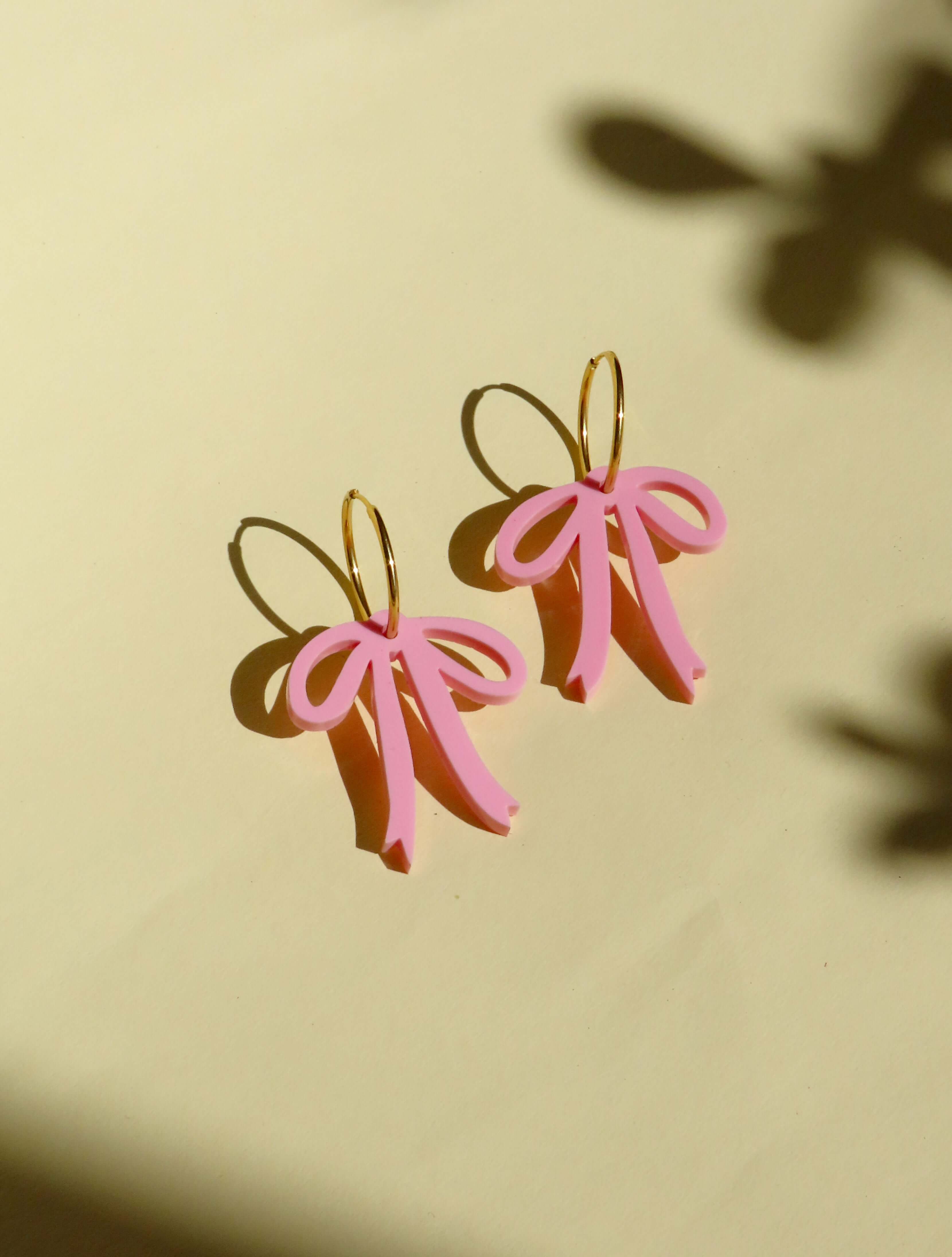 Verspielte Creolen mit rosa Schleifen, handgefertigte Statement-Ohrringe aus vergoldetem Edelstahl und Acryl.