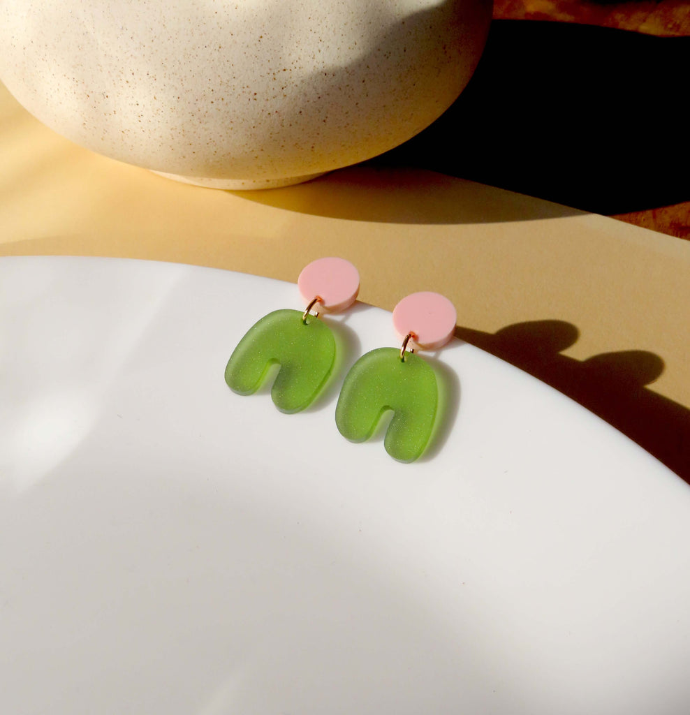Acryl-Ohrringe mit babyrosa Stecker und transluzent olivgrünem Bogenanhänger in organischer Form