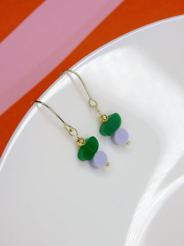 Acryl-Ohrringe in Matcha-Grün und Mauve-Flieder mit zartem Goldhaken – verspieltes Design.
