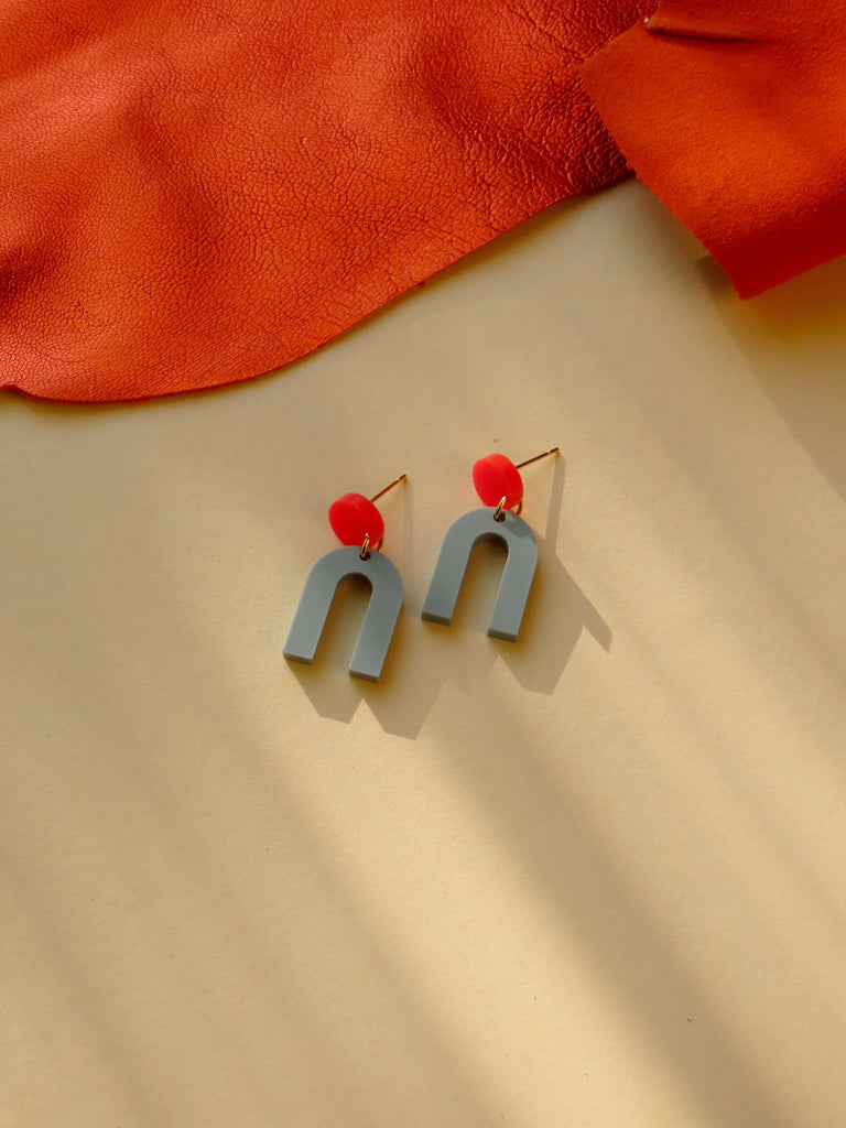 Geometrische Ohrstecker aus Acryl mit rundem roten Element und graugrünem Hufeisen-Anhänger