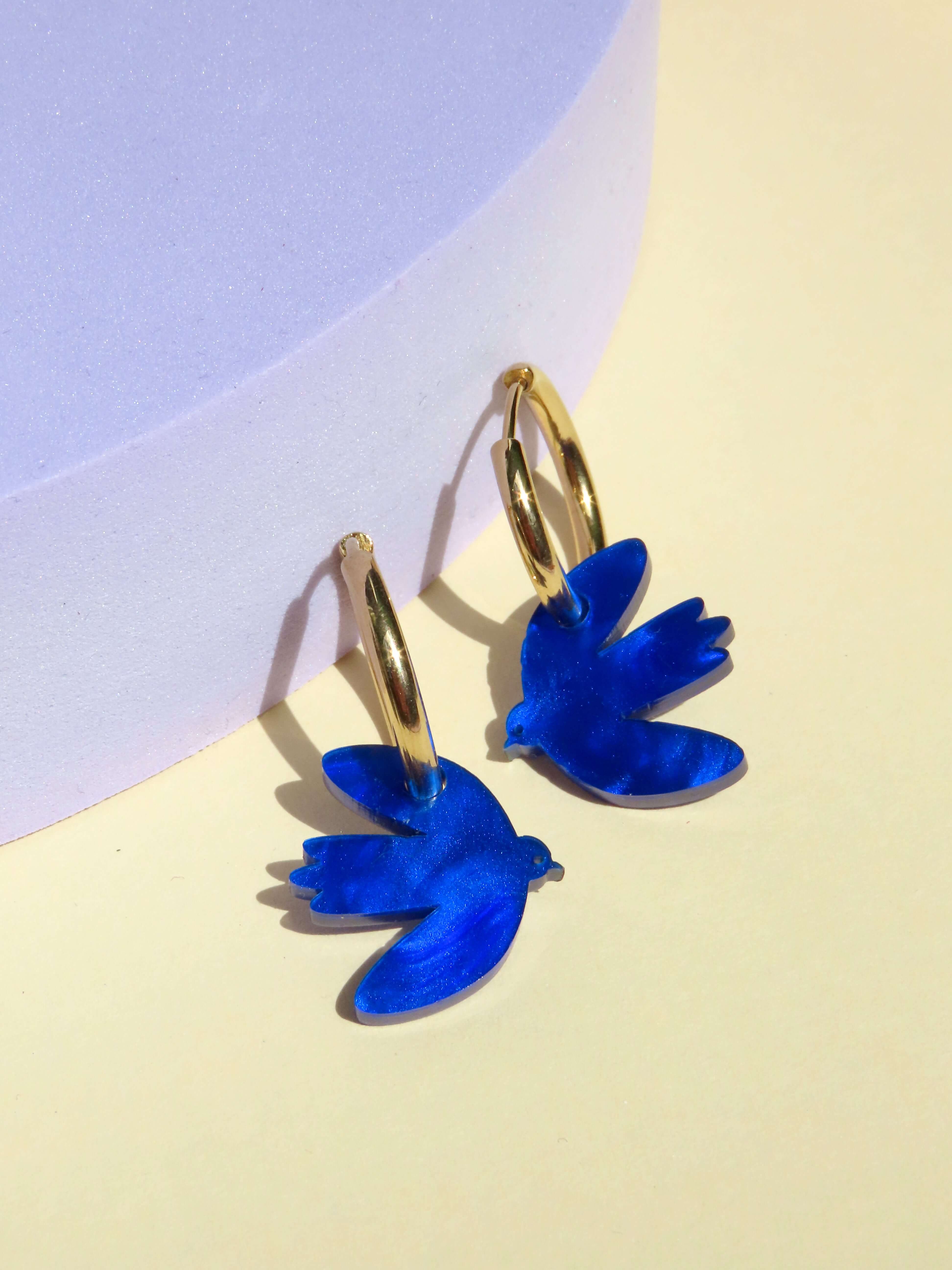 Tintenblaue Dove Creolen aus Edelstahl und Acryl, handgefertigt mit goldenen Ohrsteckern, leicht und modern.