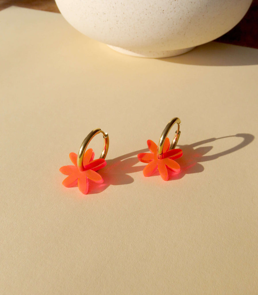 auffällige Ohrringe mit goldfarbenen Hoops und orangenen Acrylblüten