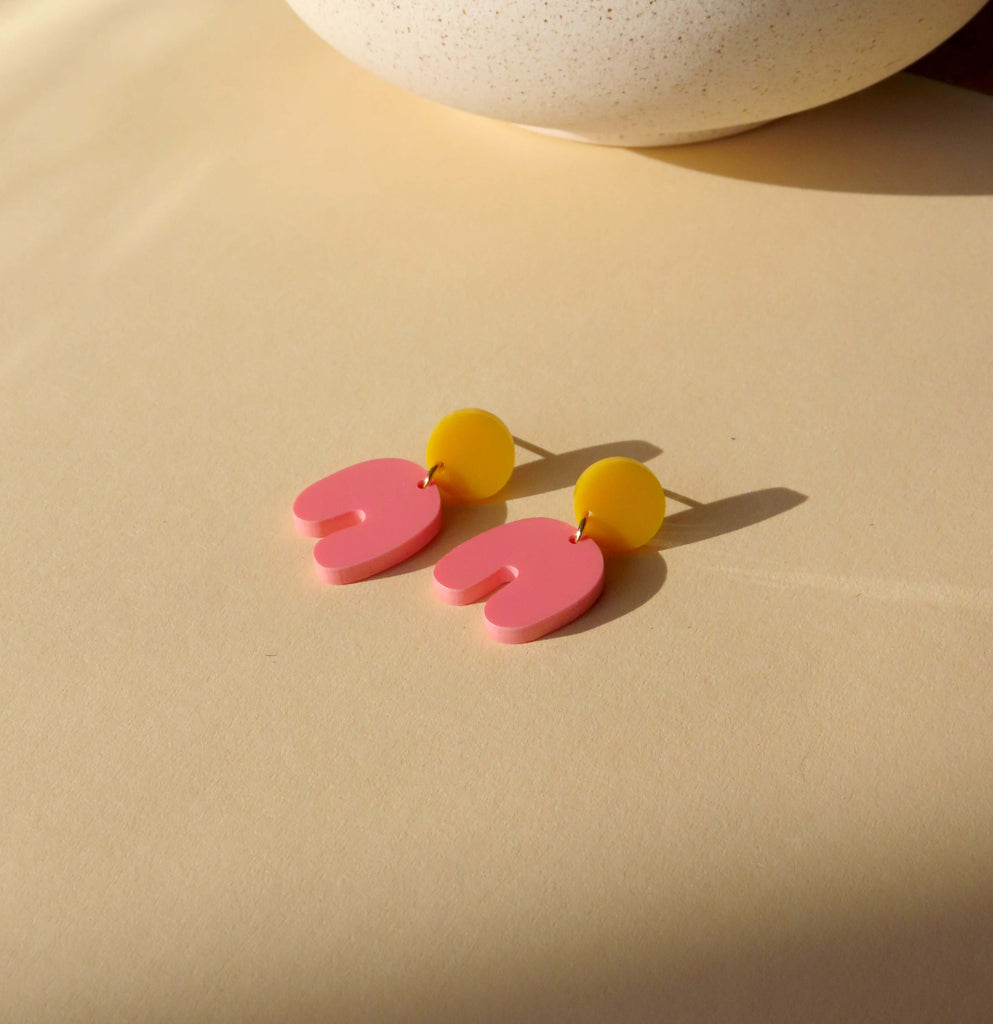 Handgemachte Ohrhänger mit pinken Bögen und gelben runden Elementen aus Acryl