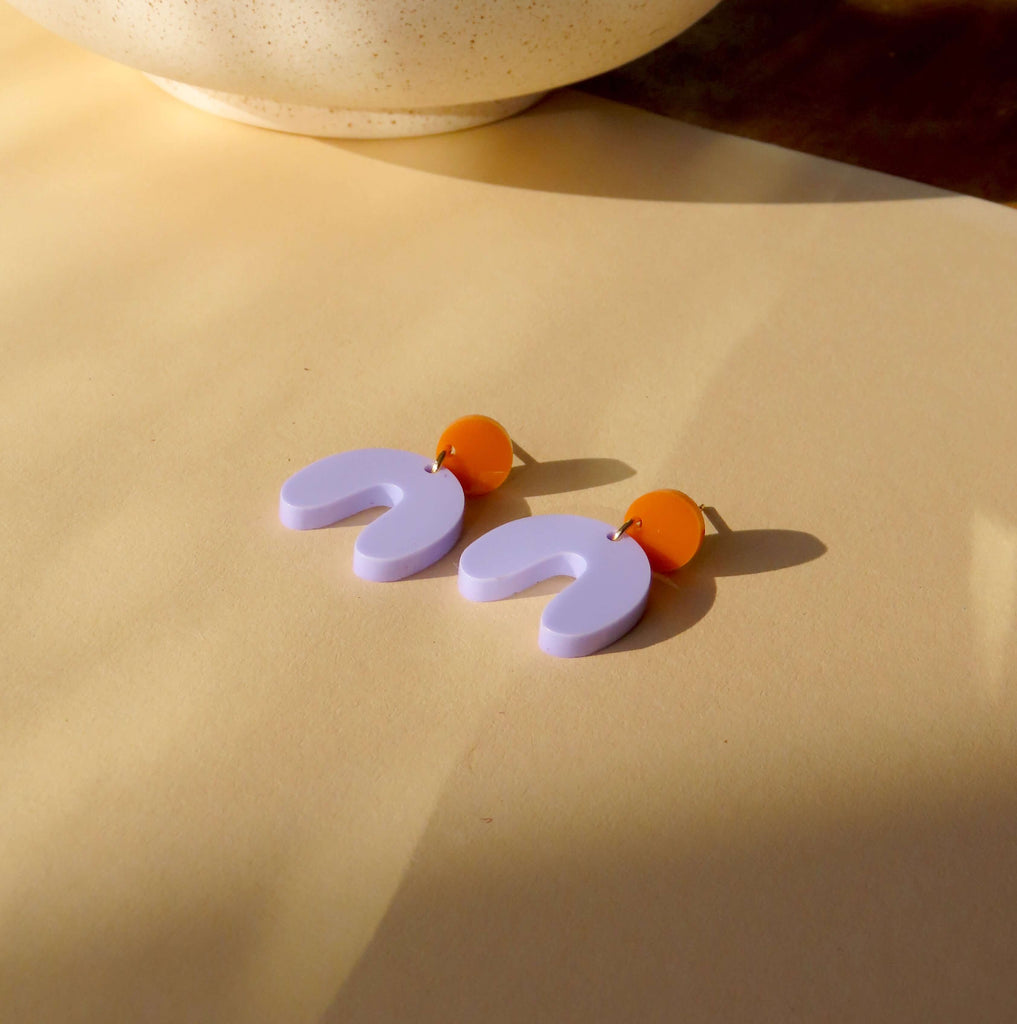 leichte Statement-Ohrringe in Bogenform mit fliederfarbenem Acrylanhänger und orangegelbem Stecker