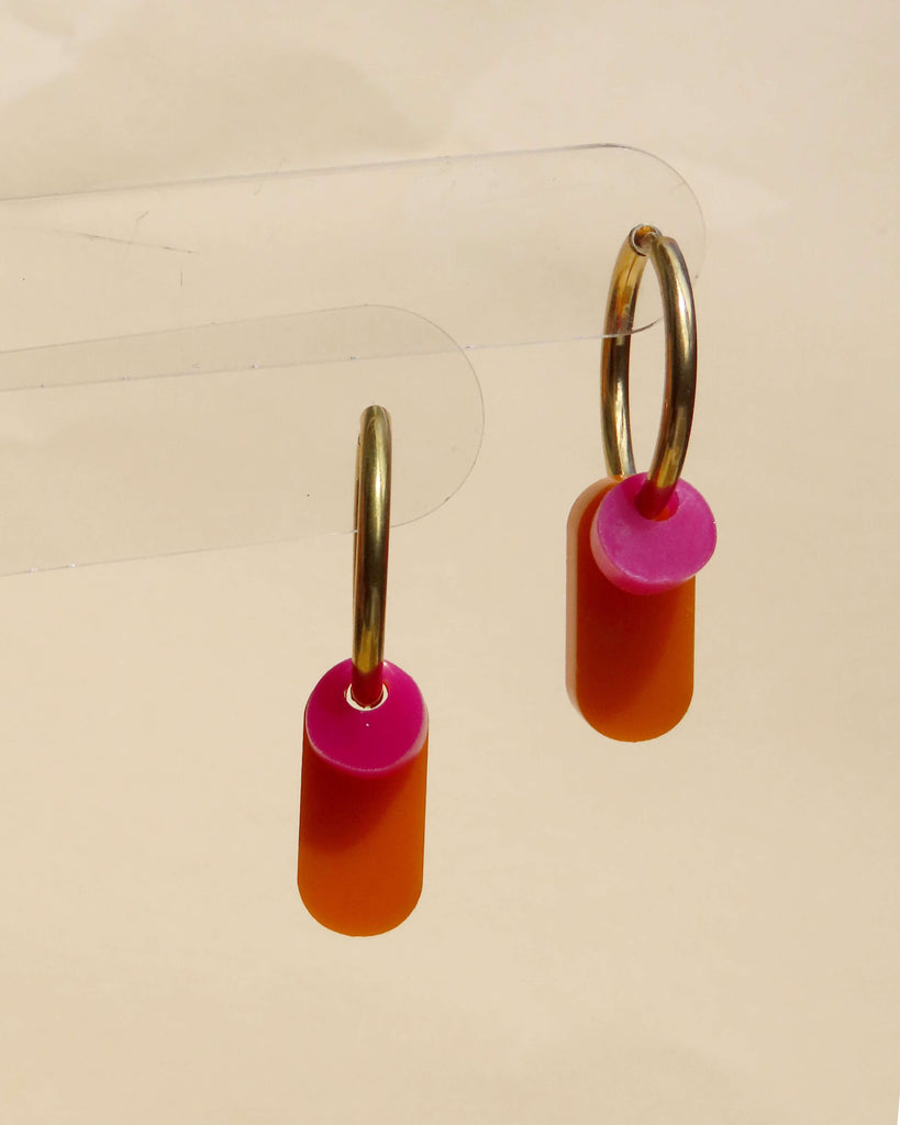 Farbige Edelstahl-Creolen mit runden pinken und länglichen orangenen Acrylelementen