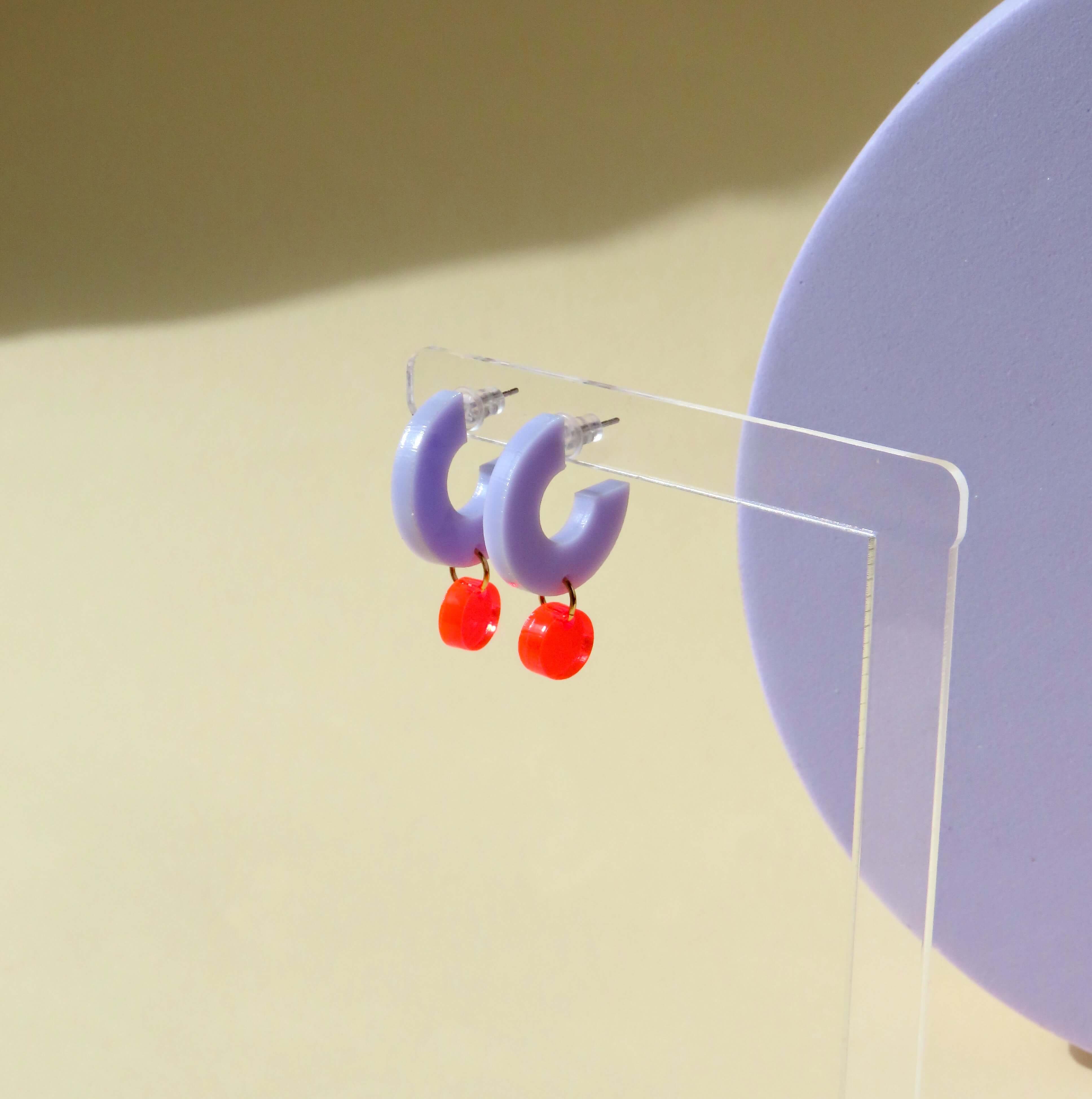 Fliederfarbene Acryl-Ohrringe mit rundem Anhänger in Neonrot und Edelstahlstiften