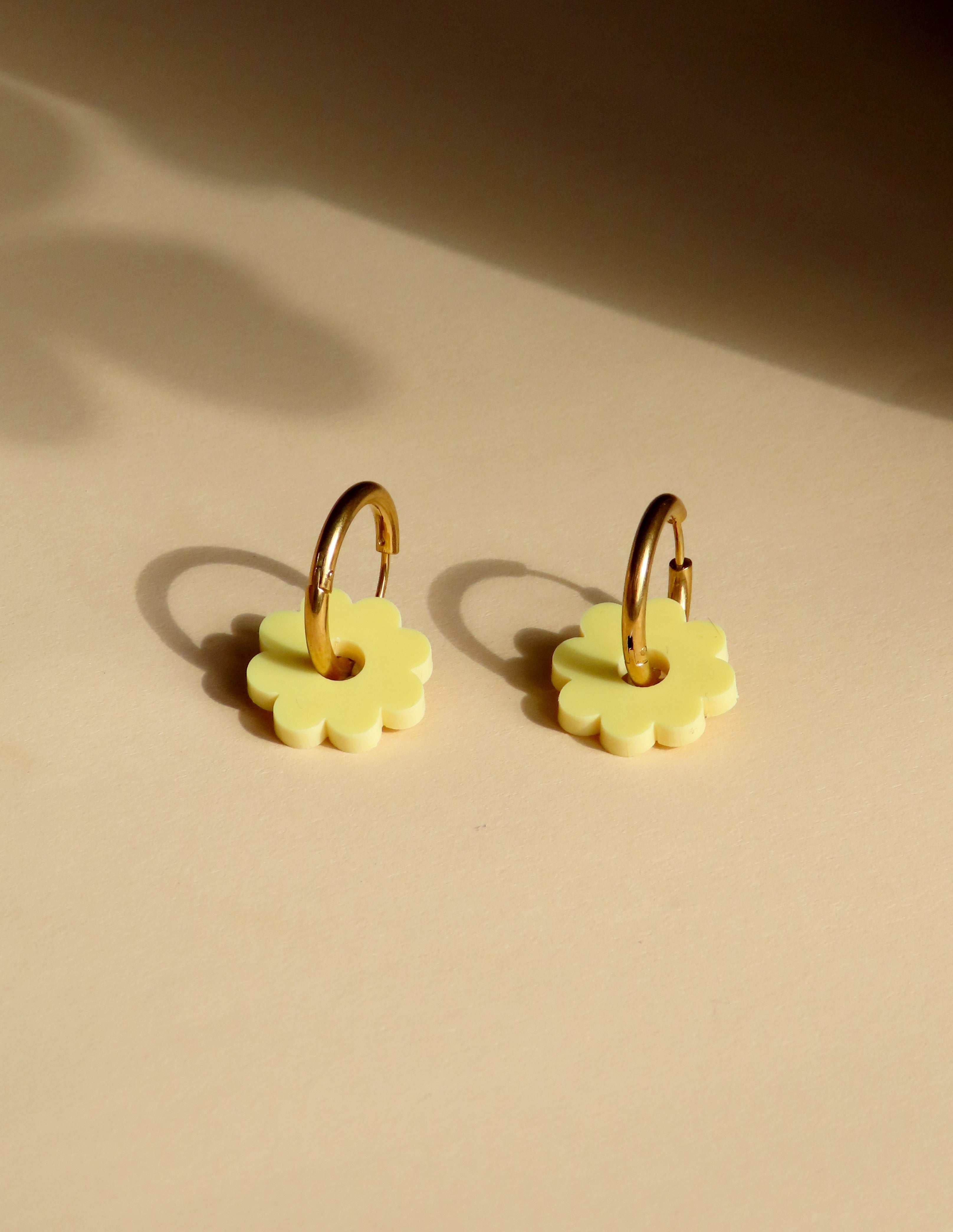 Hellgelbe Acrylblüten an goldfarbenen Creolen aus Edelstahl, runde Form mit zarten Blütenblättern