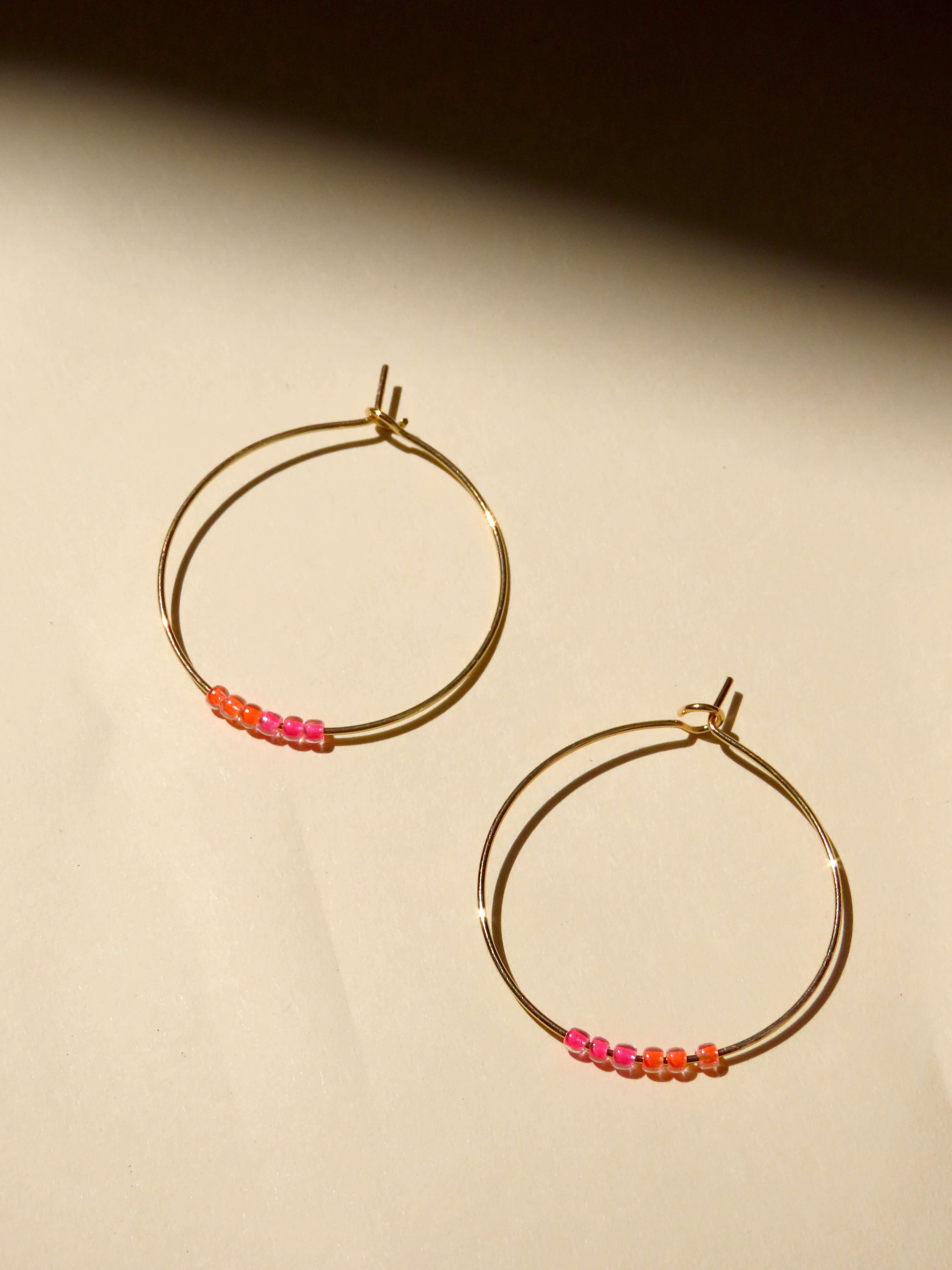 Runde Edelstahl-Hoops mit farbigen Glasperlen in Neonpink und Neonorange verziert