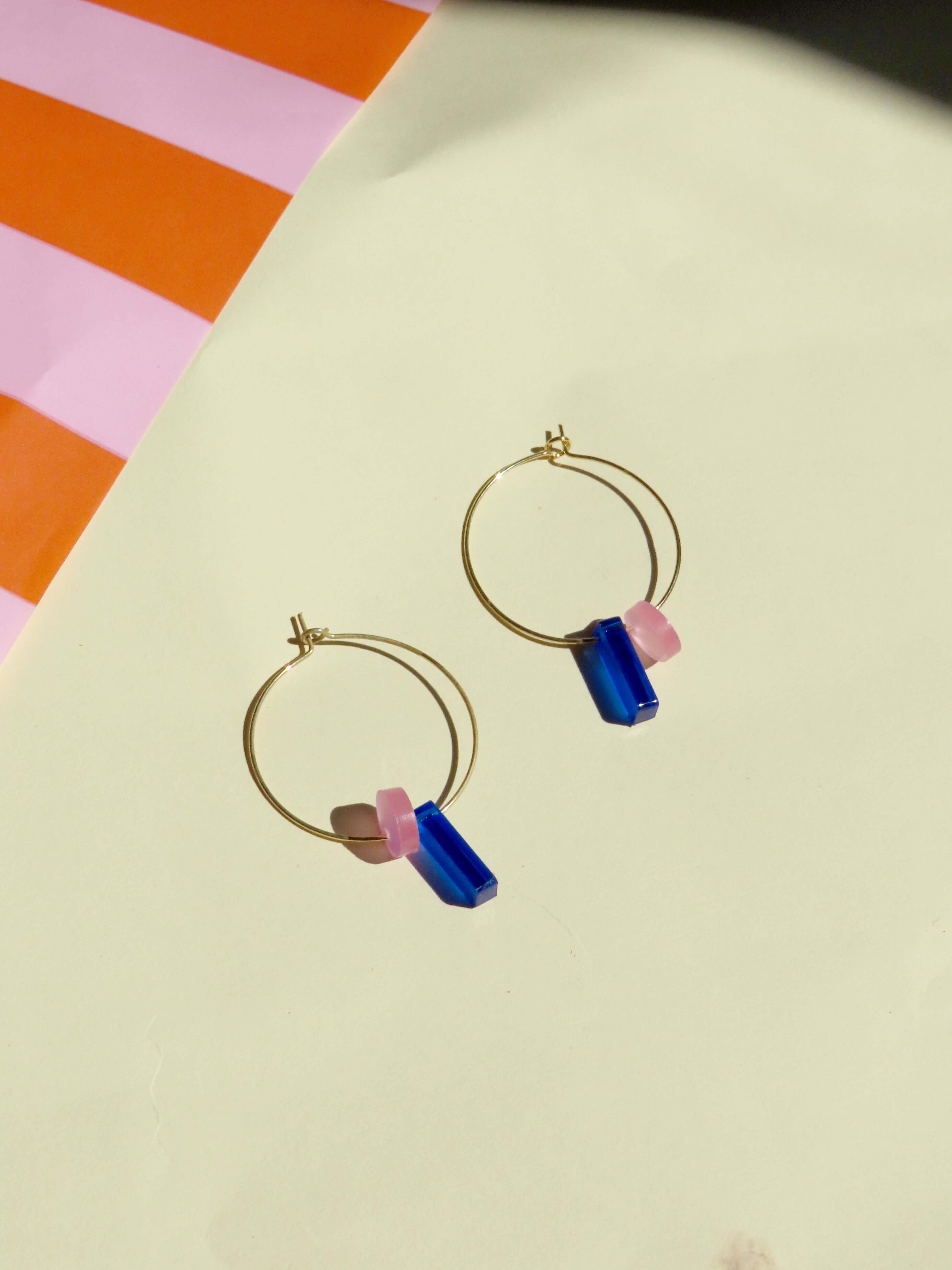 moderne creolen-ohrringe mit farbigen anhängern aus kunststoff in blau und rosa