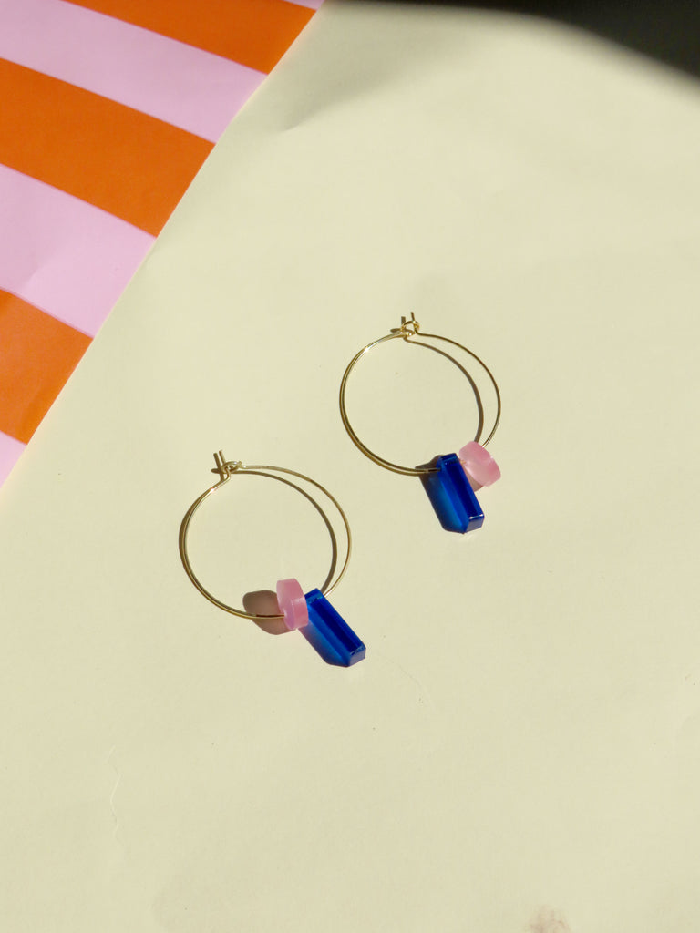 moderne creolen-ohrringe mit farbigen anhängern aus kunststoff in blau und rosa