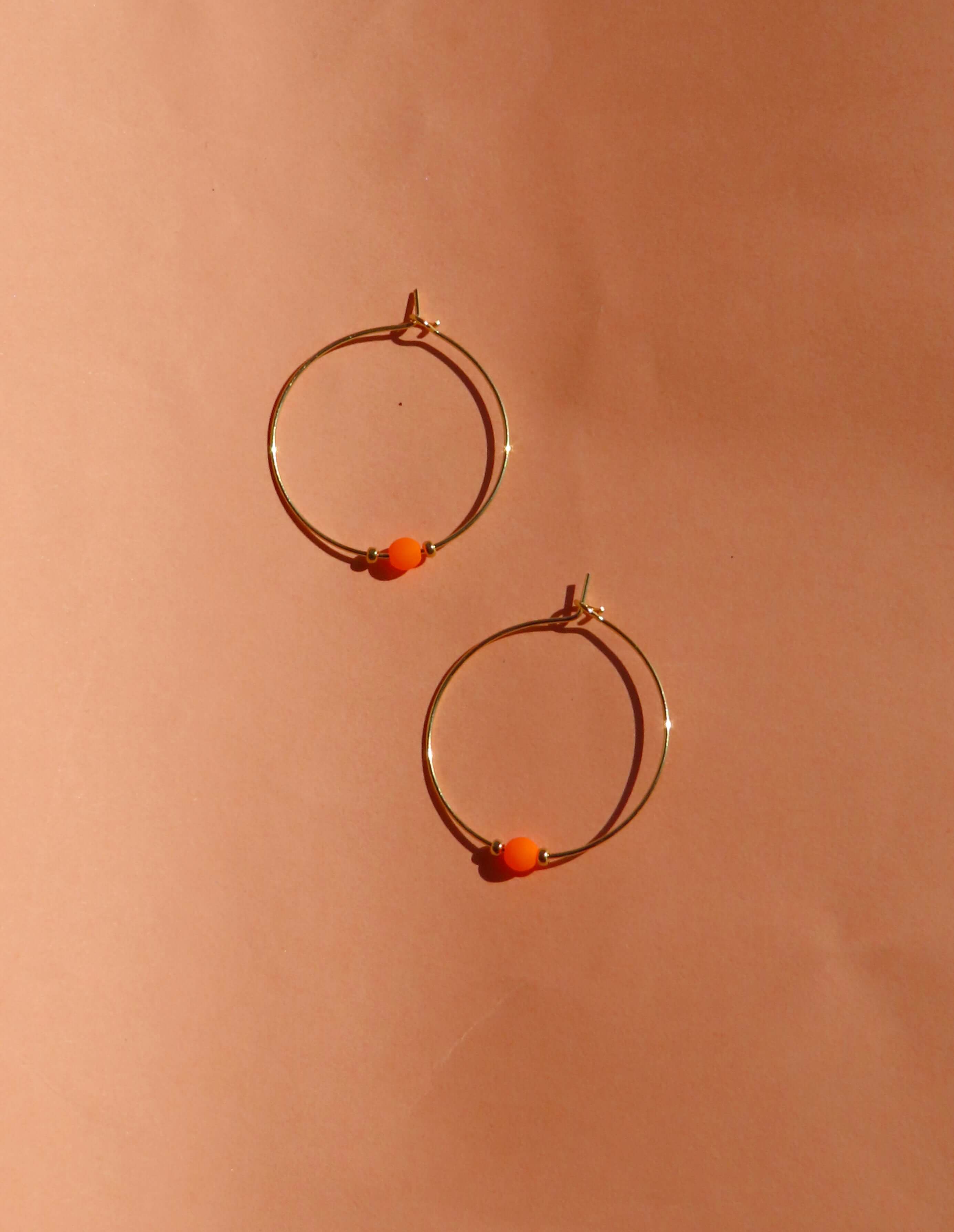 Goldfarbene Edelstahl-Creolen mit Neon-Orange Glasperle und kleinen Goldperlen