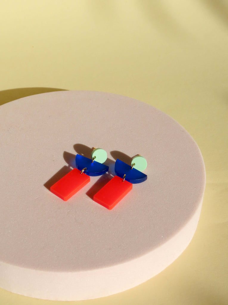 moderner geometrischer acryl-ohrring mit mintgrünem kreis, blauem halbkreis und feuerrotem rechteck