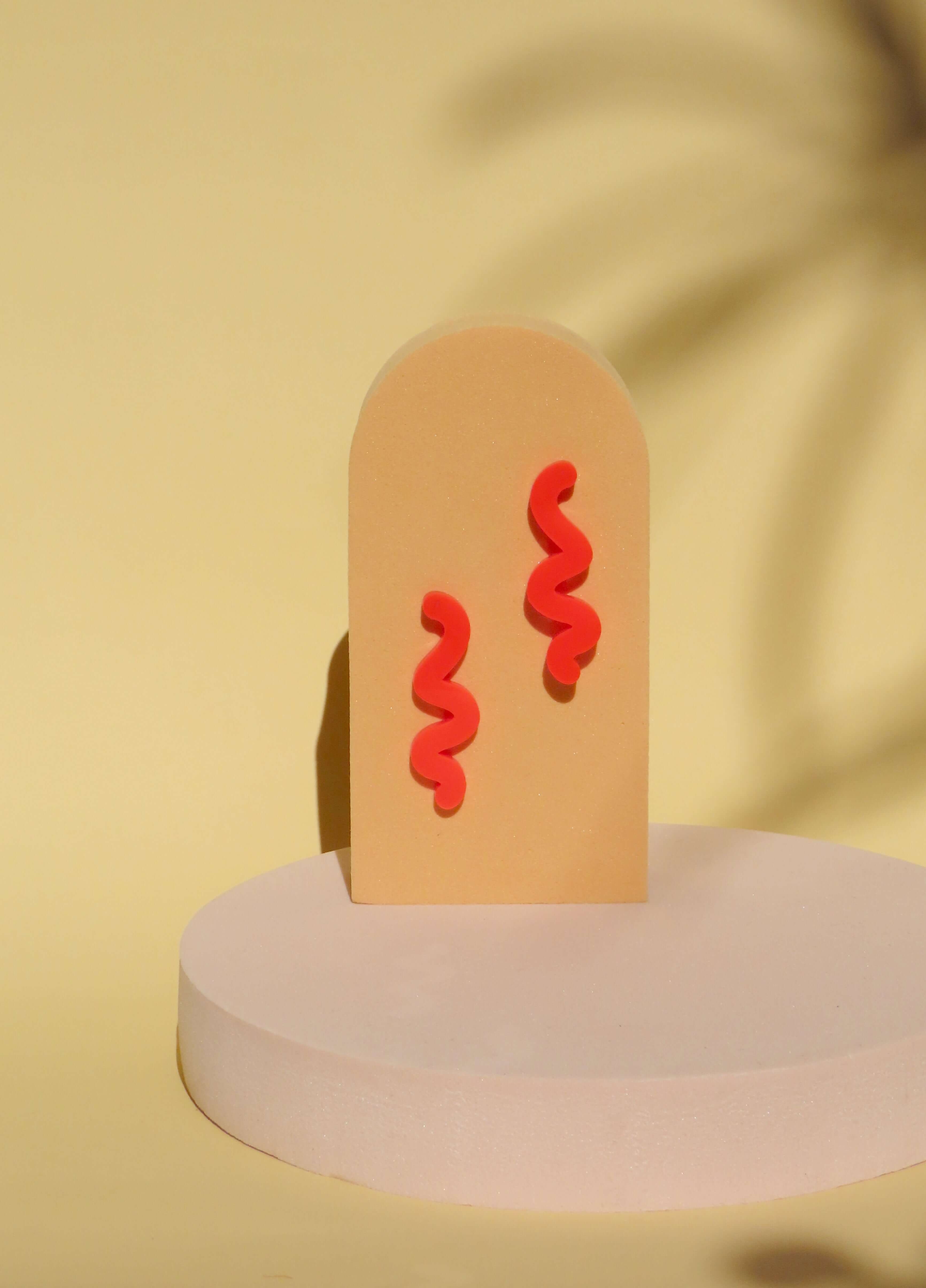 Paar feuerroter Scribble Ohrstecker aus Acryl in geschwungener Linienform mit Edelstahlsteckern