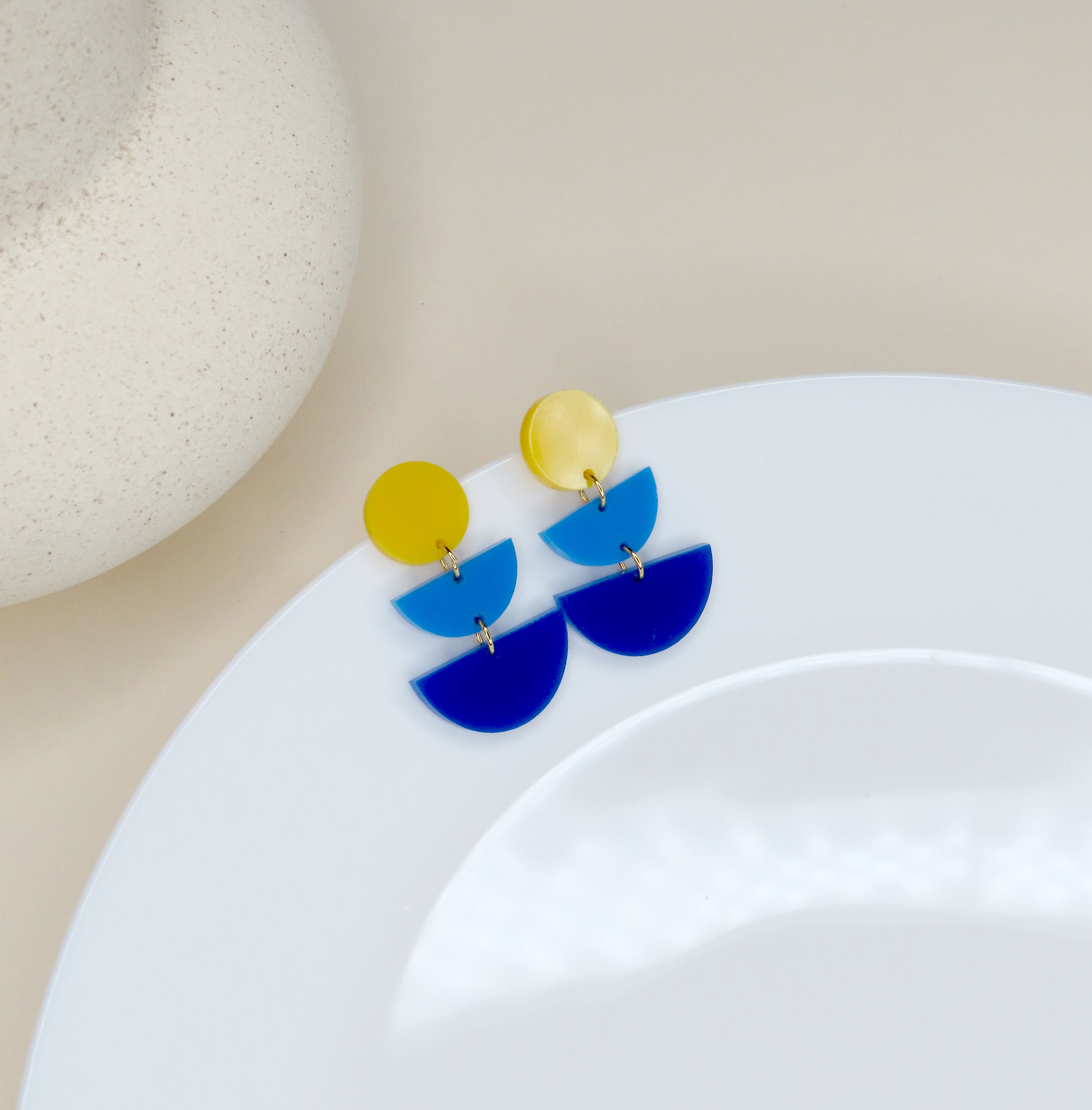 Farbig verspielte Acryl-Ohrringe mit gelbem Kreis und blauen Halbbögen in gestufter Anordnung