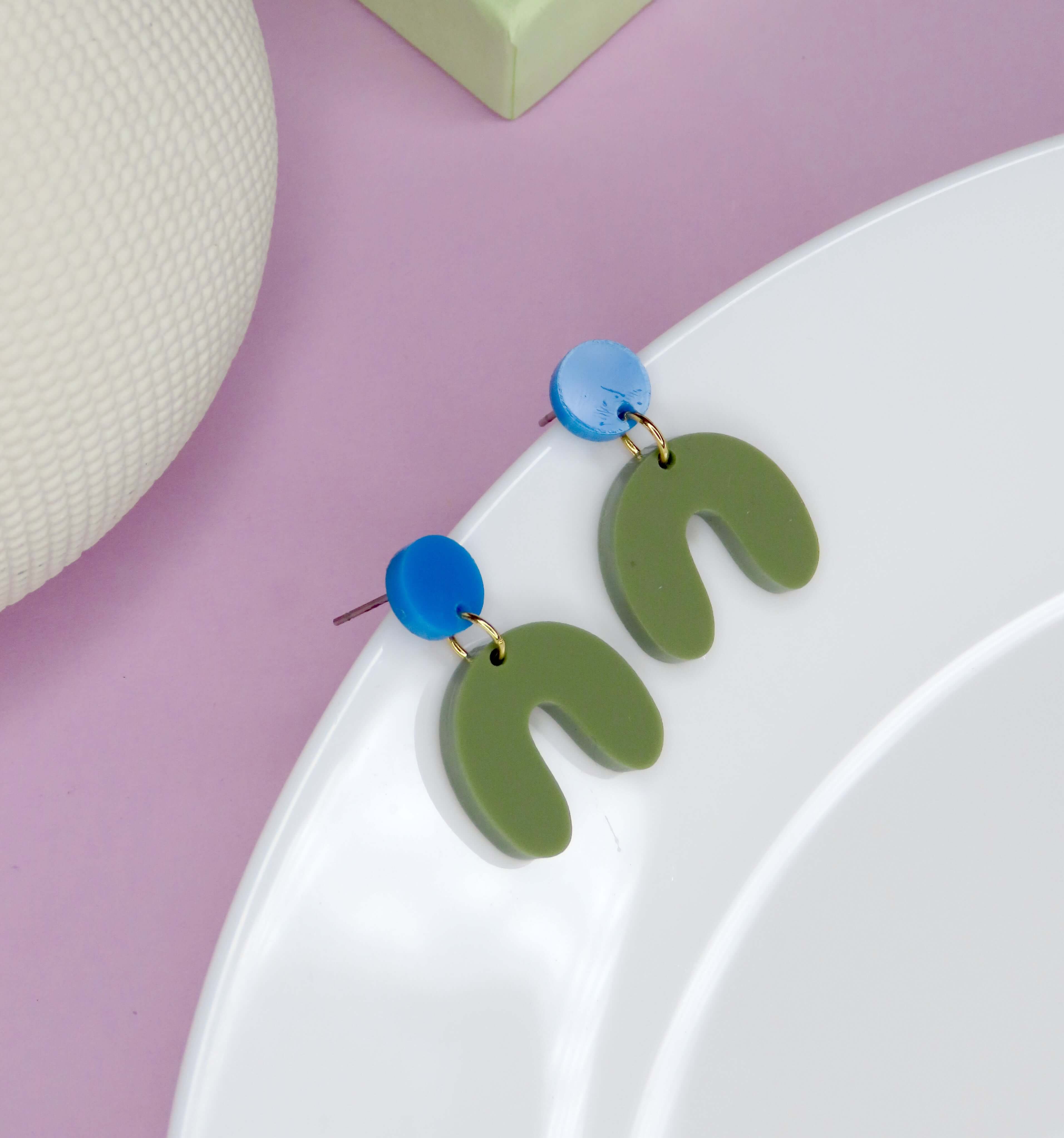 Geometrische Ohrringe aus Acryl in Azurblau und Olive mit Edelstahlsteckern, bestehend aus rundem Kreis und organischer Bogenform