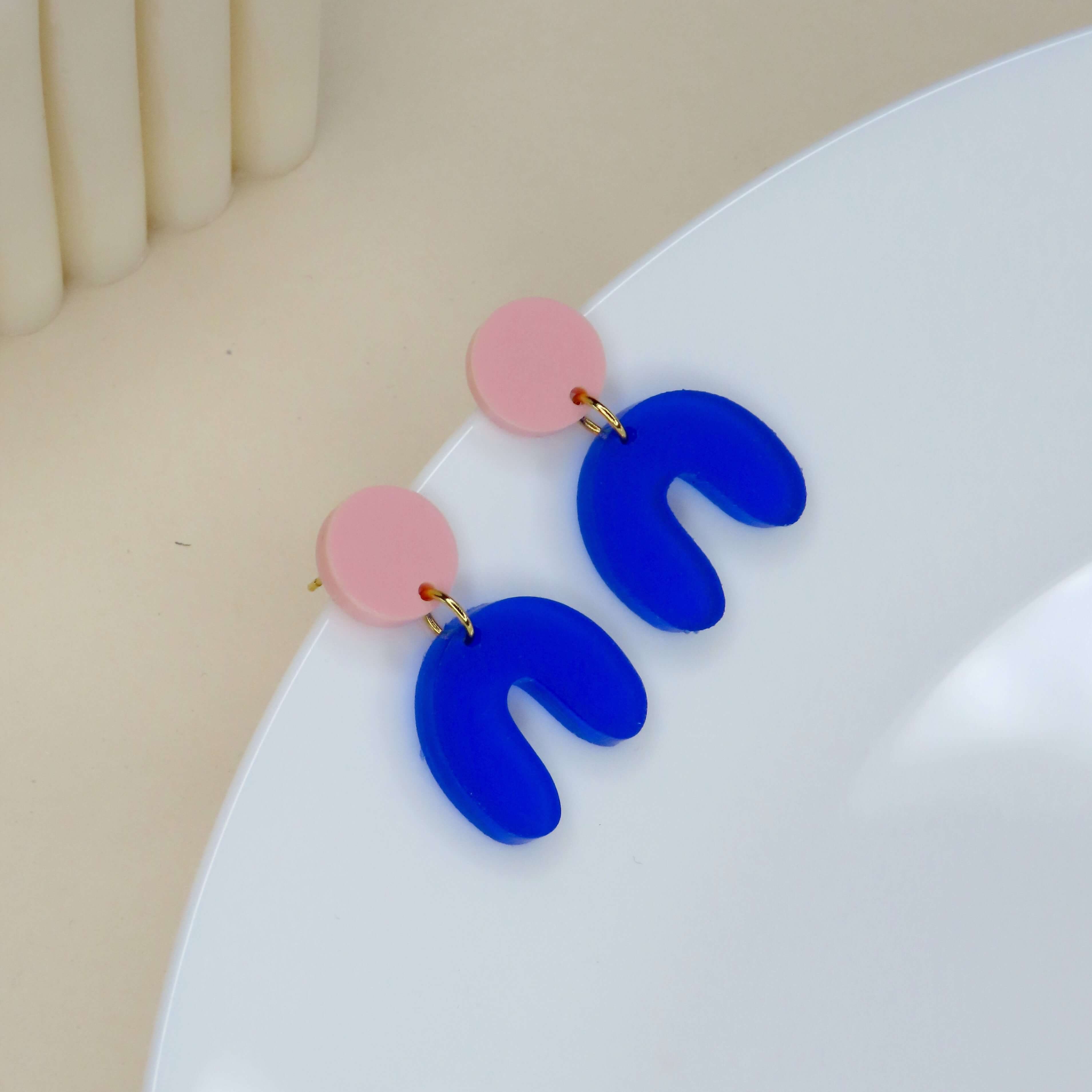 Zweifarbige Acryl-Ohrringe in Bogenform mit hellrosa Kreis und geschwungenem blauen Element