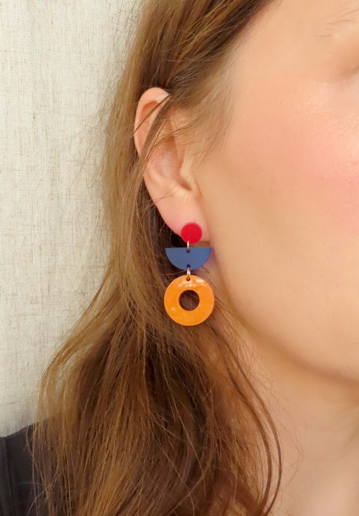 Farbintensive Ohrringe aus Acryl mit geometrischen Formen: rote Punkte, blaue Halbkreise und auffällige orangefarbene Ringe