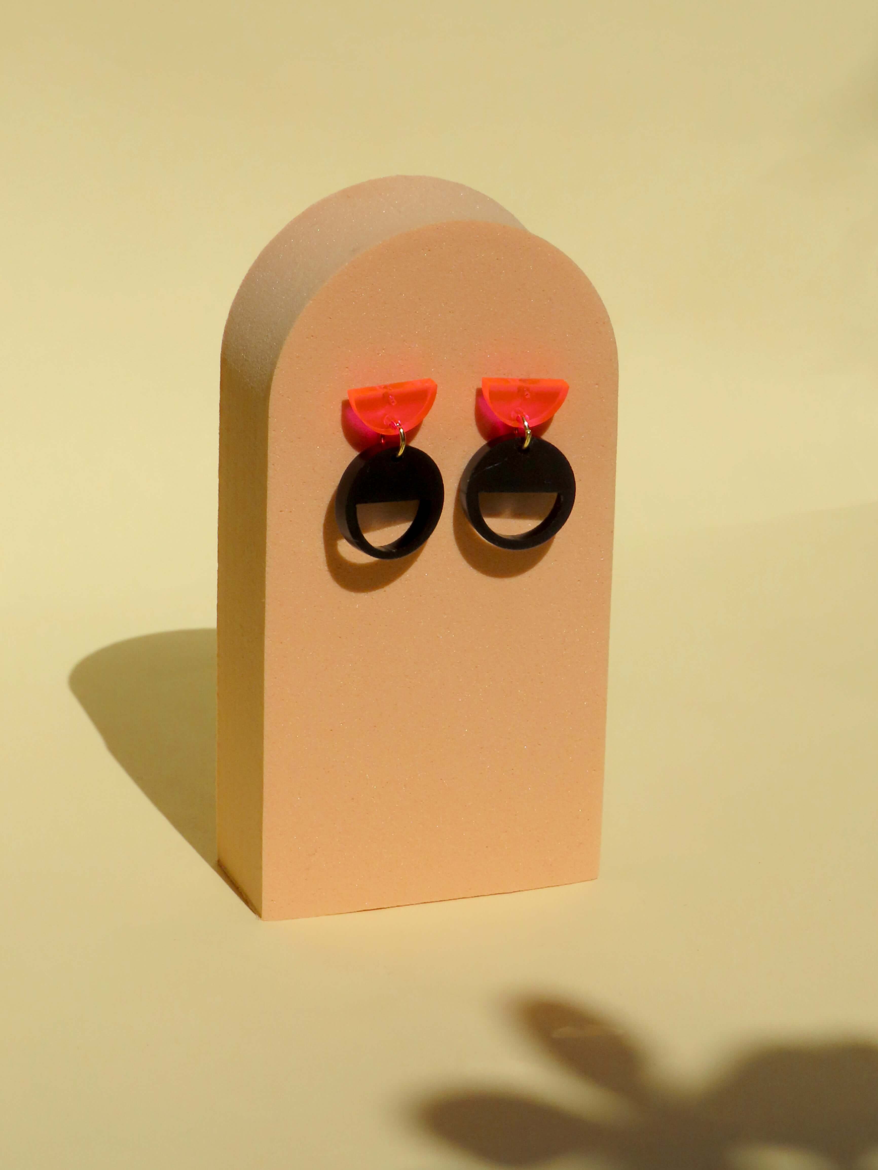 Geometrische Ohrstecker mit Halbkreis in Neon-Pinke und schwarzem Kreis