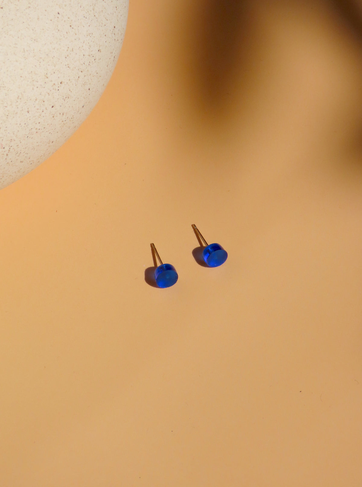 wei tintenblaue Ink Pop Ohrstecker mit runden Acrylscheiben und seitlich sichtbaren Steckerstiften vor einer hellen Keramikschale
