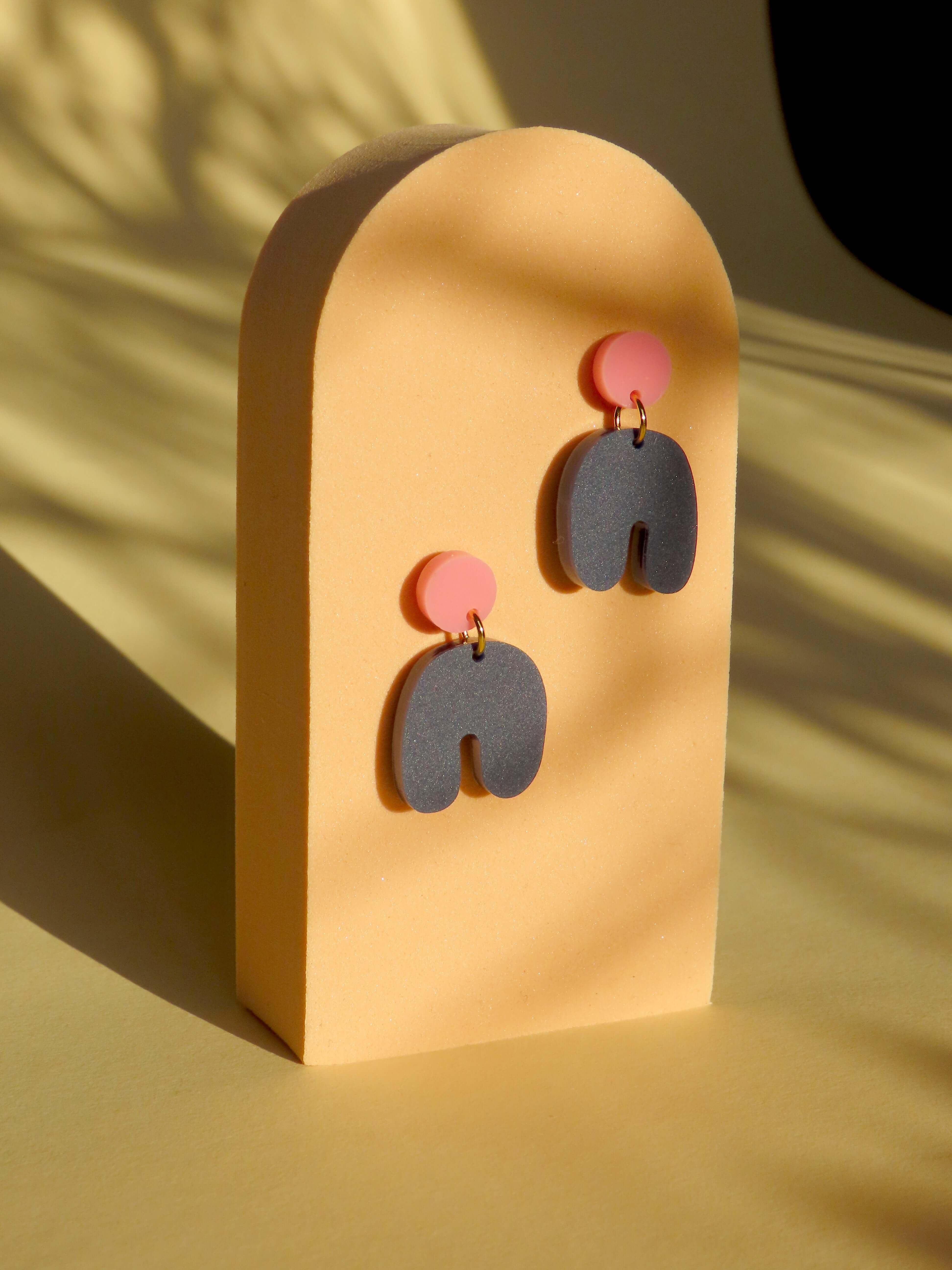 Handgemachte Bogen Ohrringe aus Acryl, rosa runder Stecker kombiniert mit dunkelblauem geschwungenem Element
