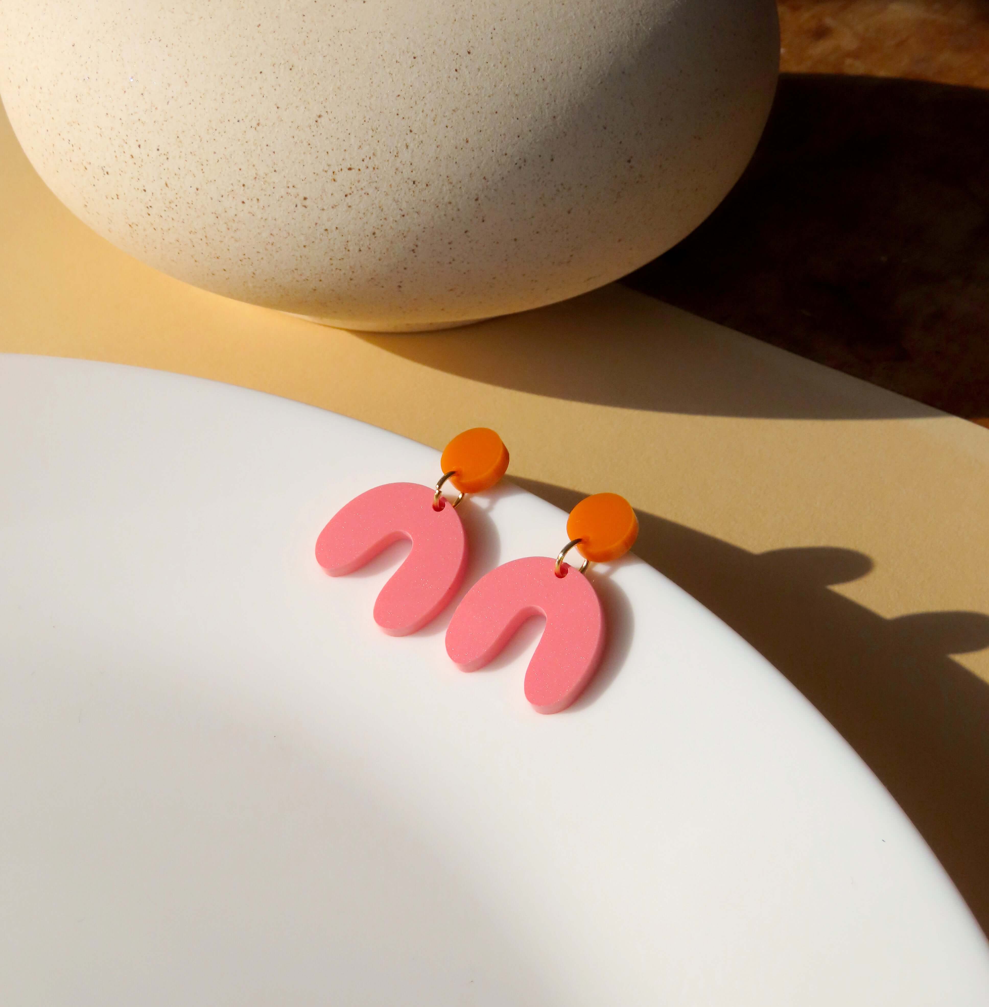 Kleine Acryl Ohrringe mit rundem Stecker in Orangegelb und bogenförmigem Anhänger in Rosa