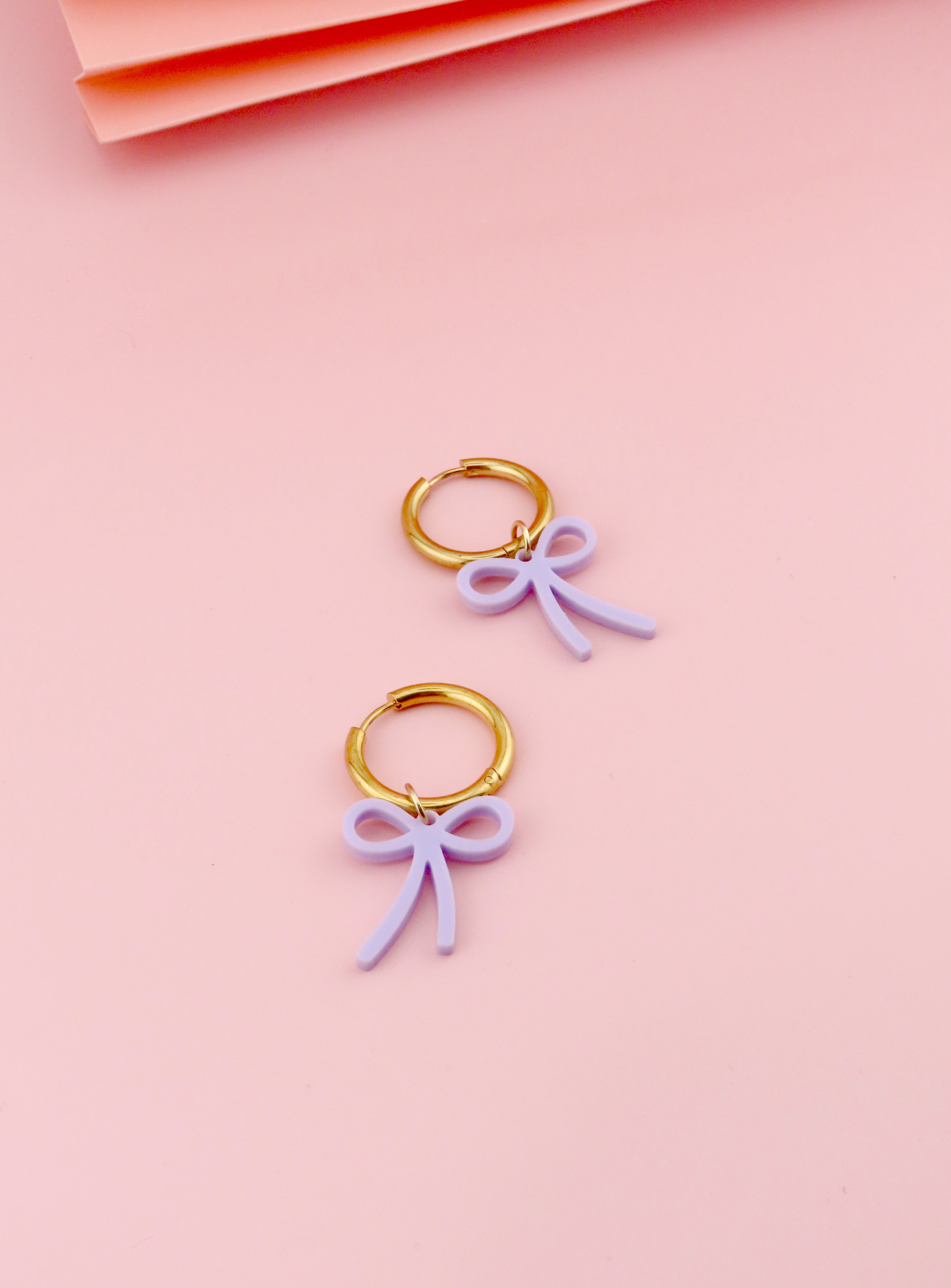 Creolen aus vergoldetem Edelstahl mit fliederfarbenem Acrylanhaenger in klarer Schleifenform