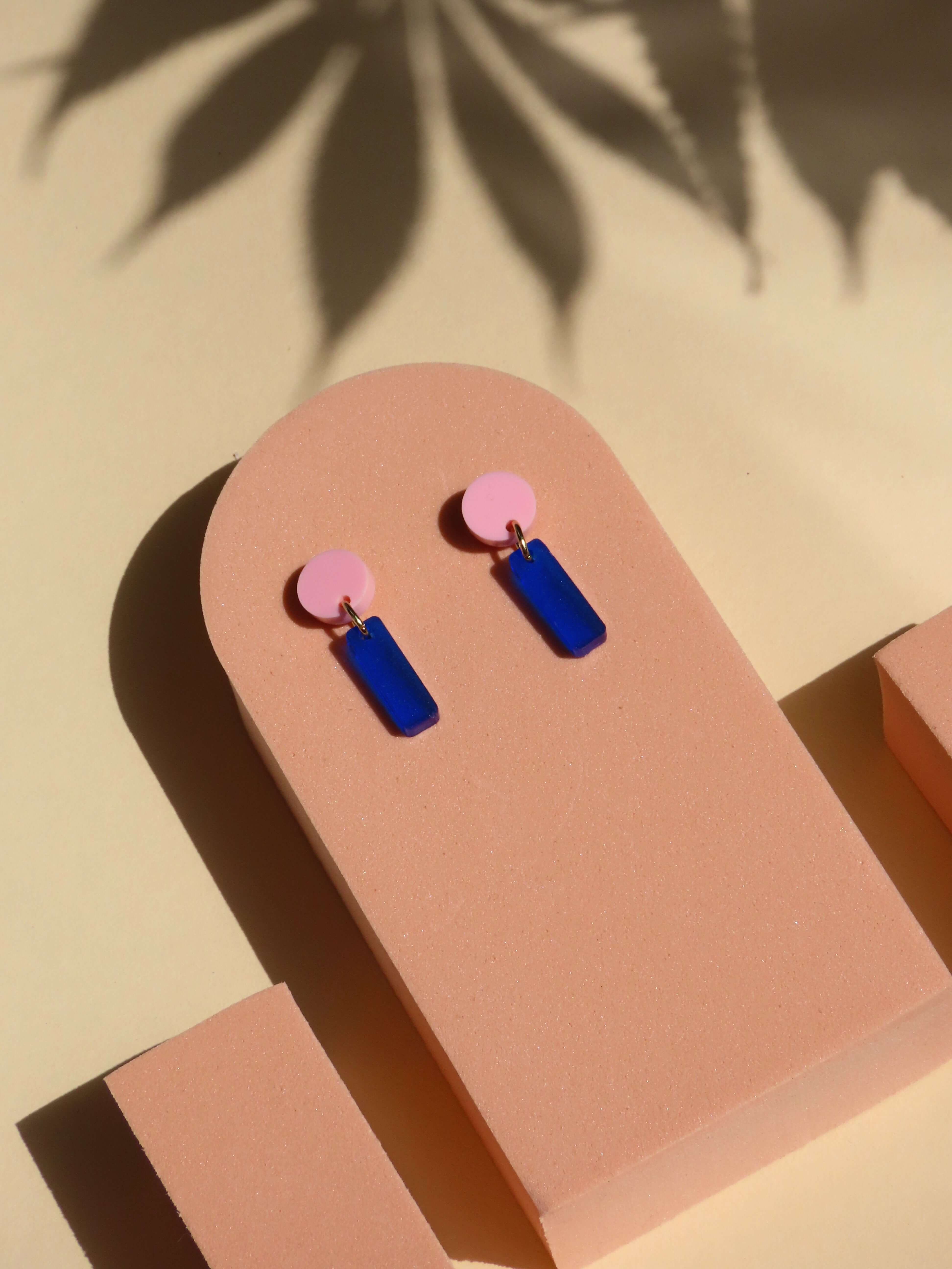 Geometrische Ohrringe aus Acryl mit rosa Kreis und rechteckigem Anhänger in Tintenblau an Edelstahlsteckern