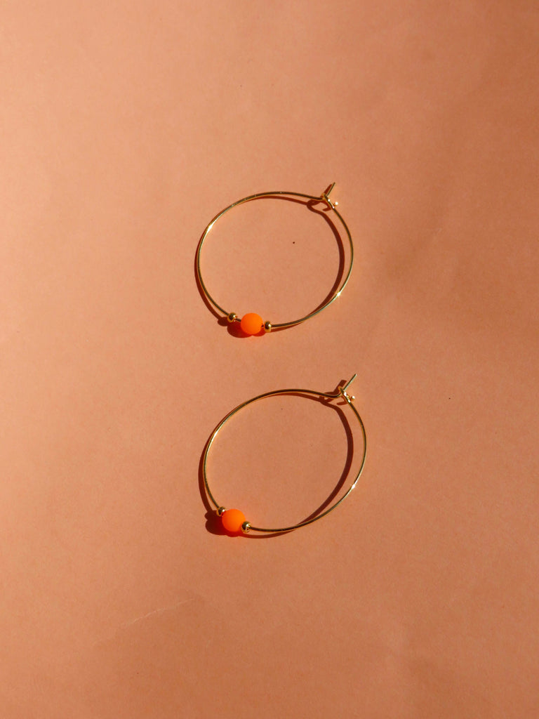 Elegante Creolen goldfarben mit leuchtender Neon-Orange Glasperle, eingefasst von zwei Goldperlen