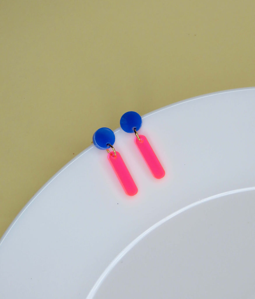 Neonfarbene Ohrstecker mit grafischer Form: runder Stecker und abgerundeter Rechteckanhänger in leuchtendem Pink