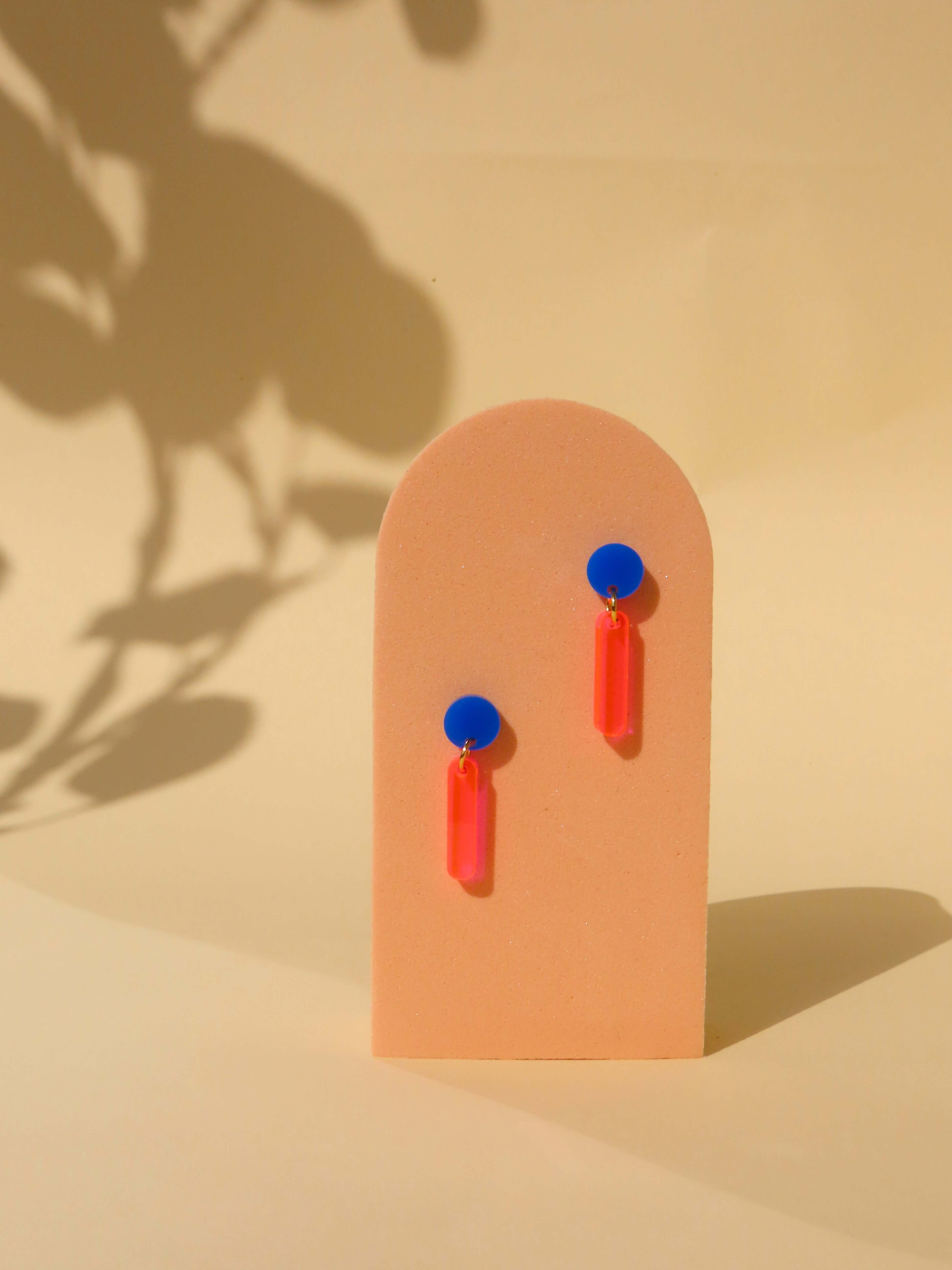 Ohrstecker mit rundem blauen Acrylstecker und leuchtend neonpinken, länglichen Anhängern aus Acryl