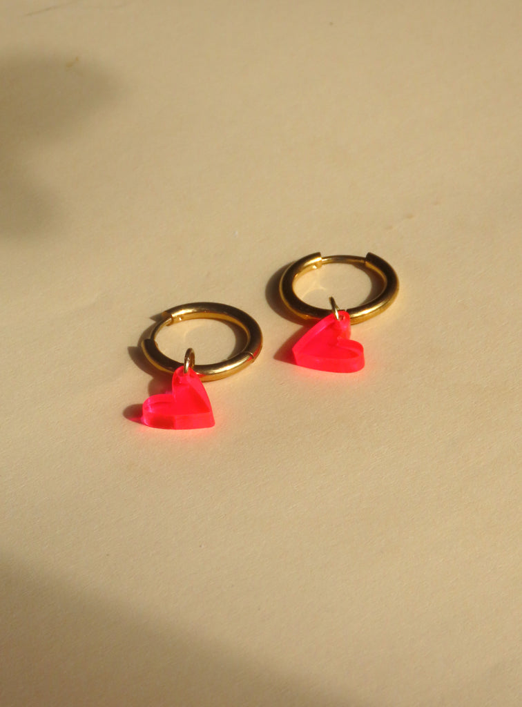 Verspielte Creolen mit transparenten Herzanhängern in Neon Pink und goldglänzendem Edelstahl
