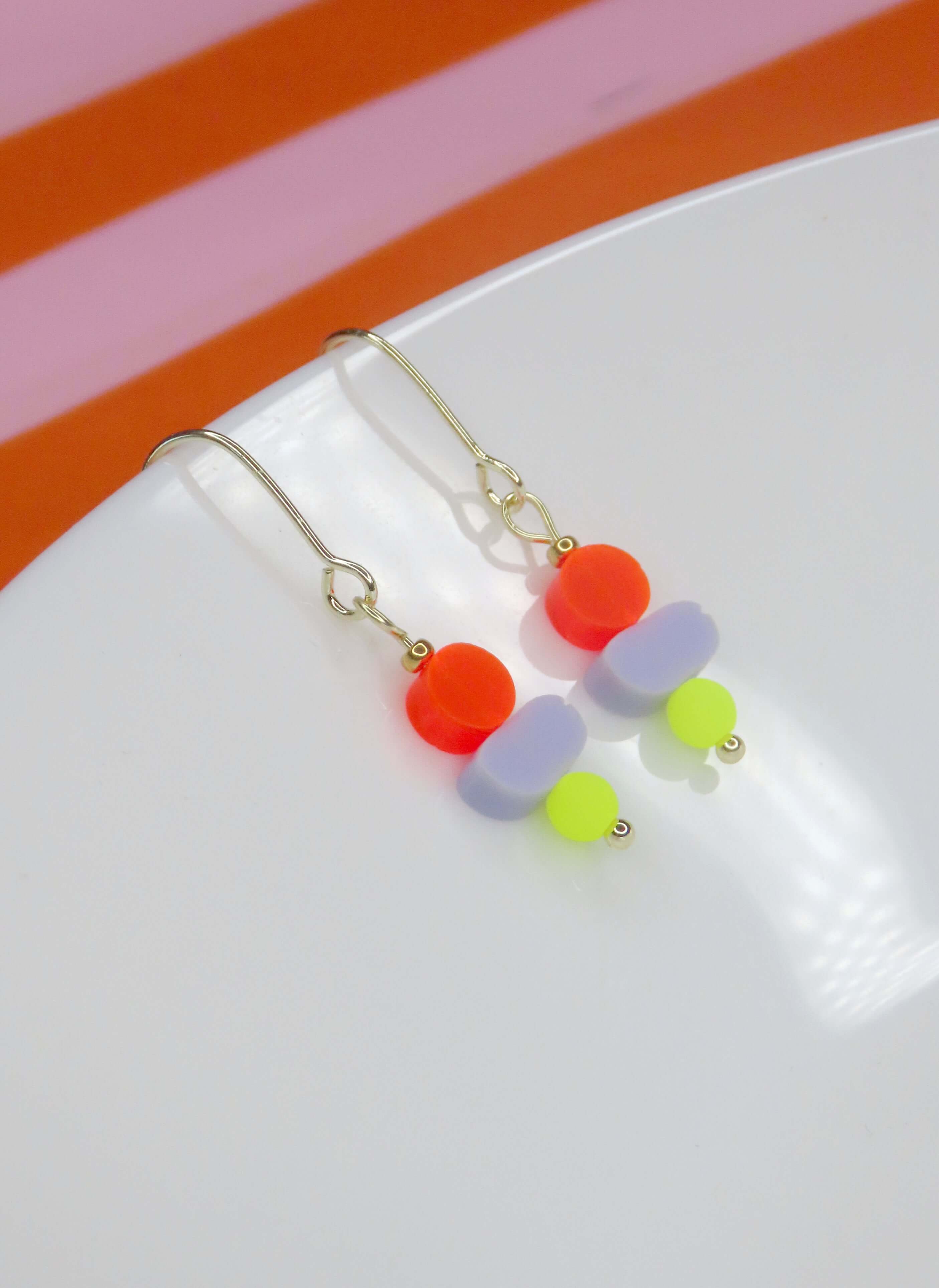 Farbenfroher Ohrhänger mit drei verschiedenfarbigen Acrylperlen und goldfarbenem Ohrhaken