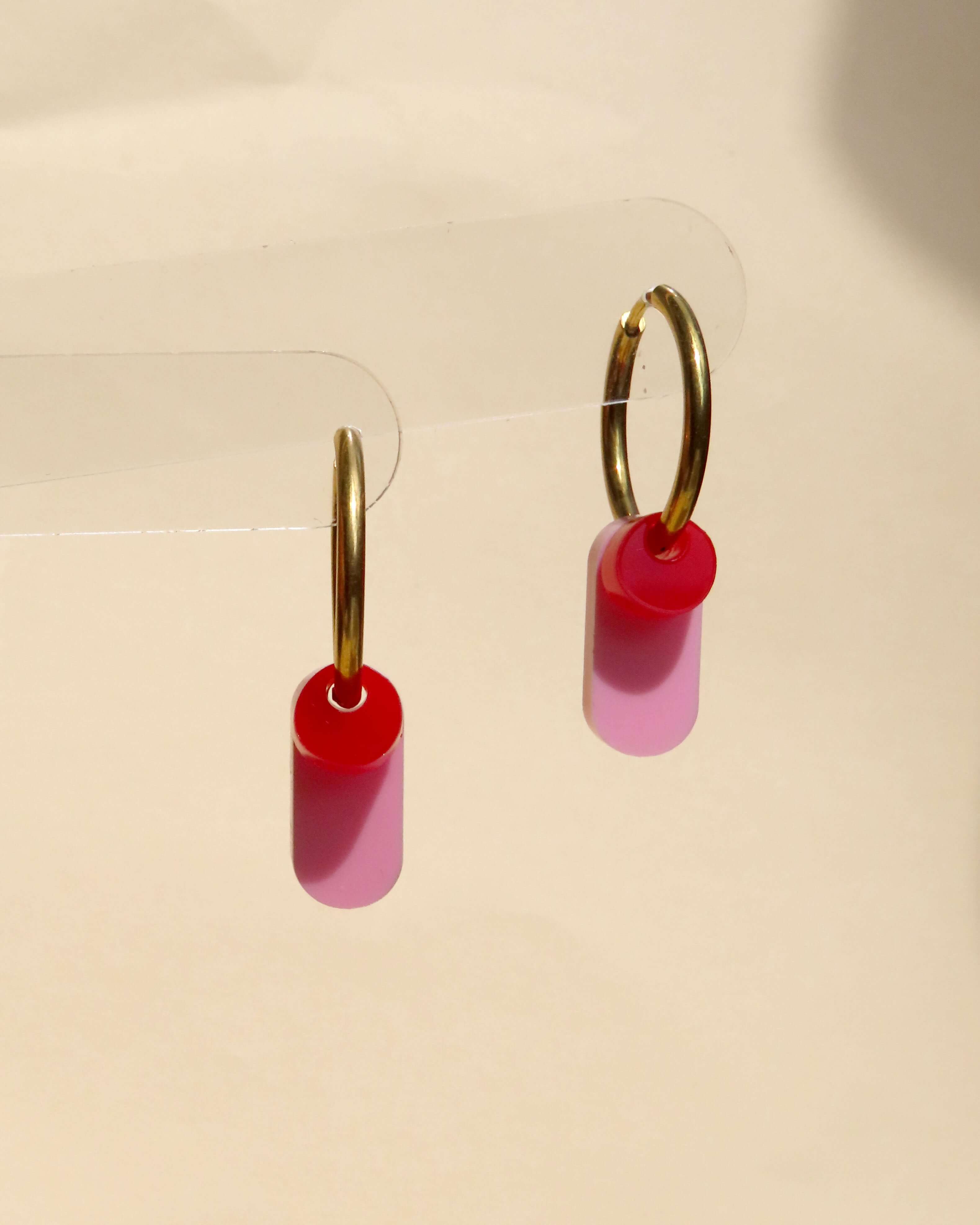 Goldfarbene Creolen mit röhrenförmigem rosa Acrylanhänger und rundem roten Element
